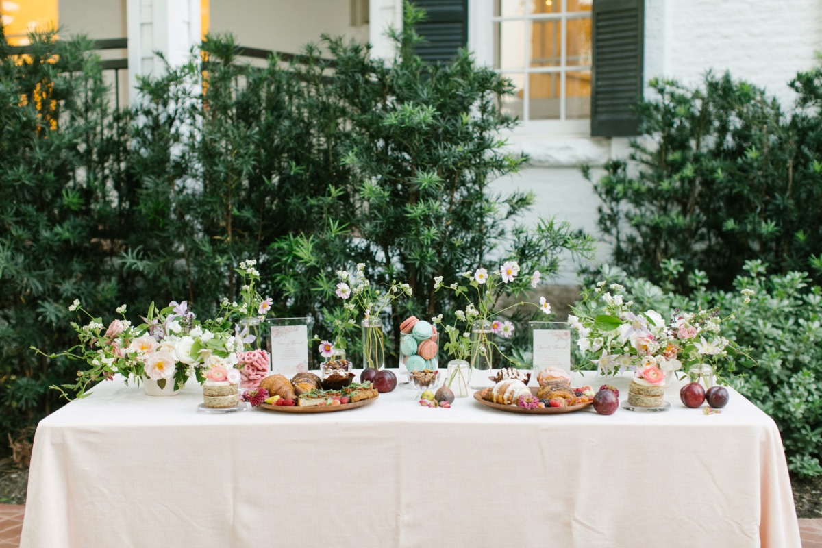 Elegant outdoor dessert table with floral arrangements and treats