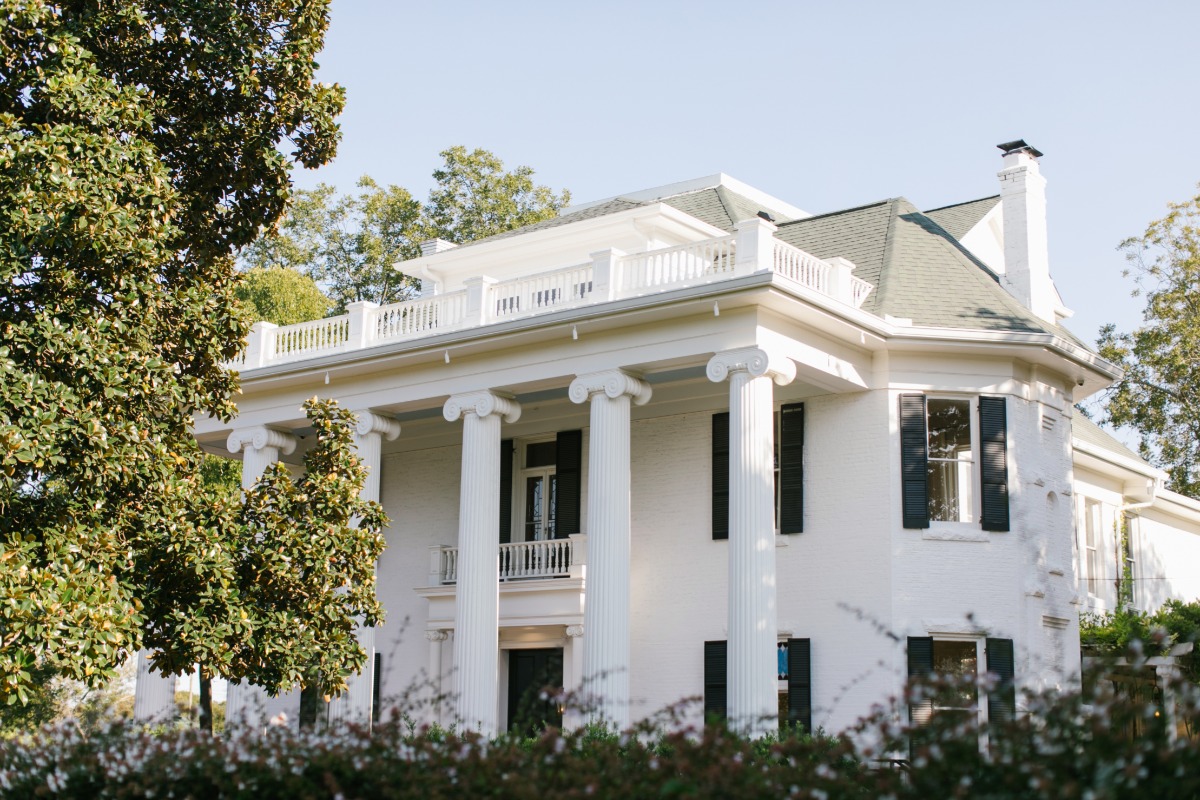 Elegant white mansion with tall columns and lush landscaping
