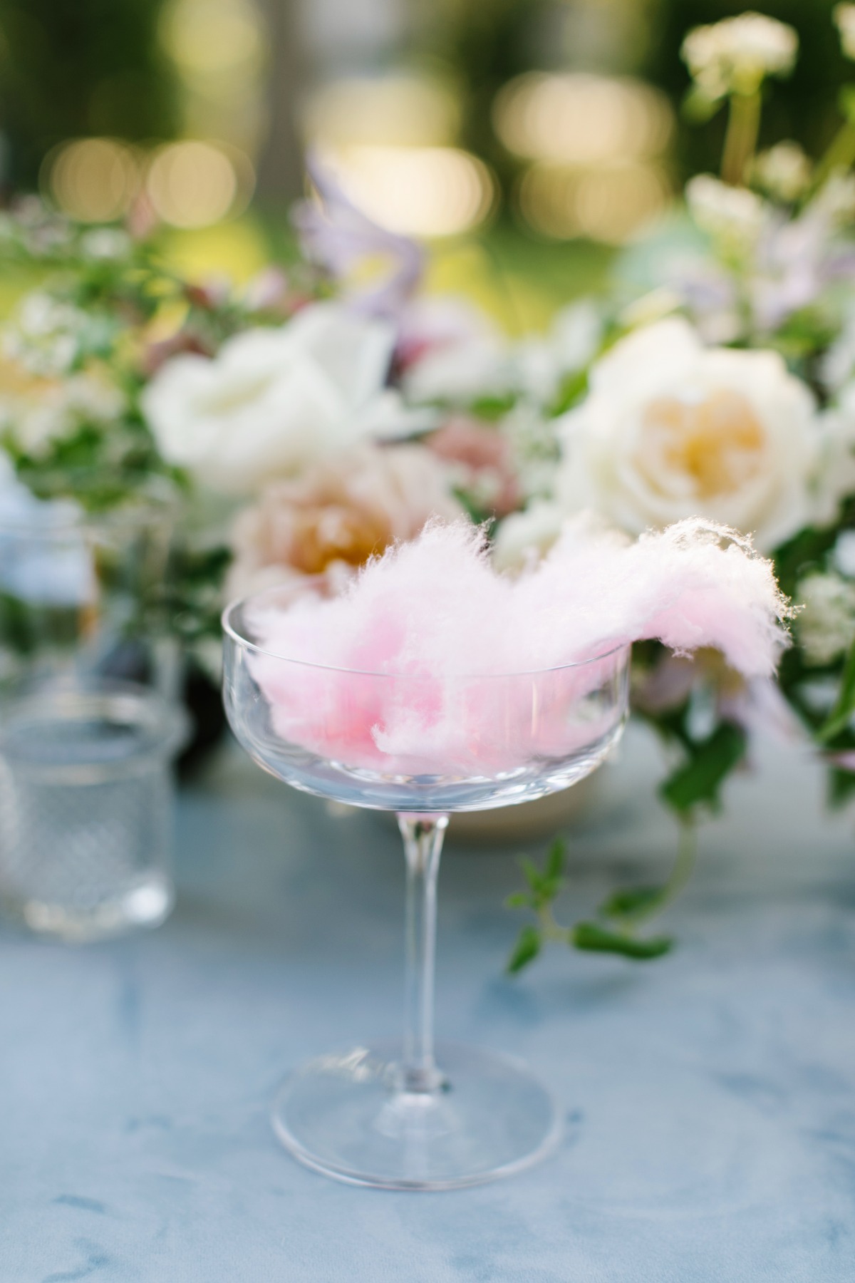 Cotton candy in a glass with flowers in the background