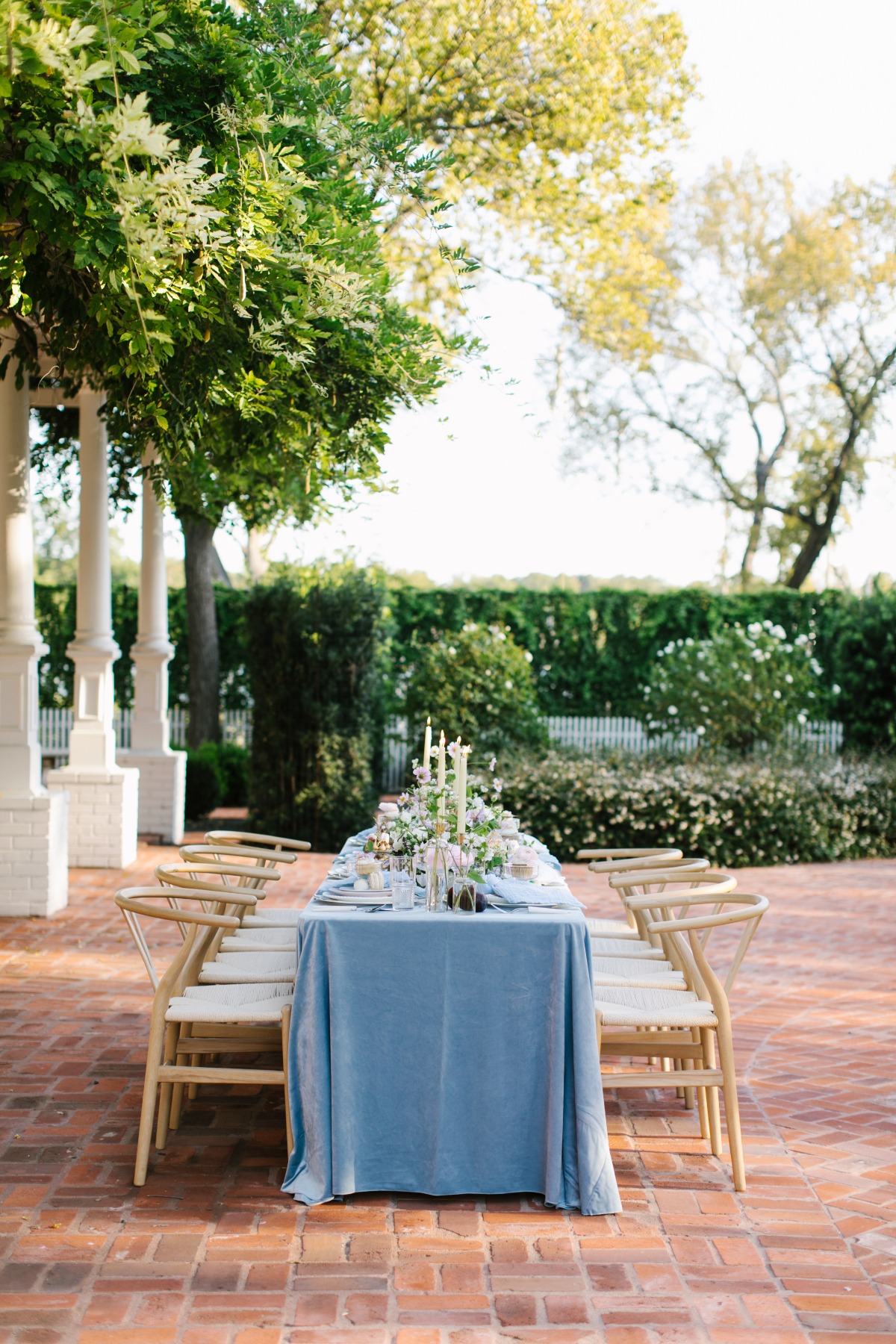 Elegant outdoor dining table setting with blue tablecloth and flowers