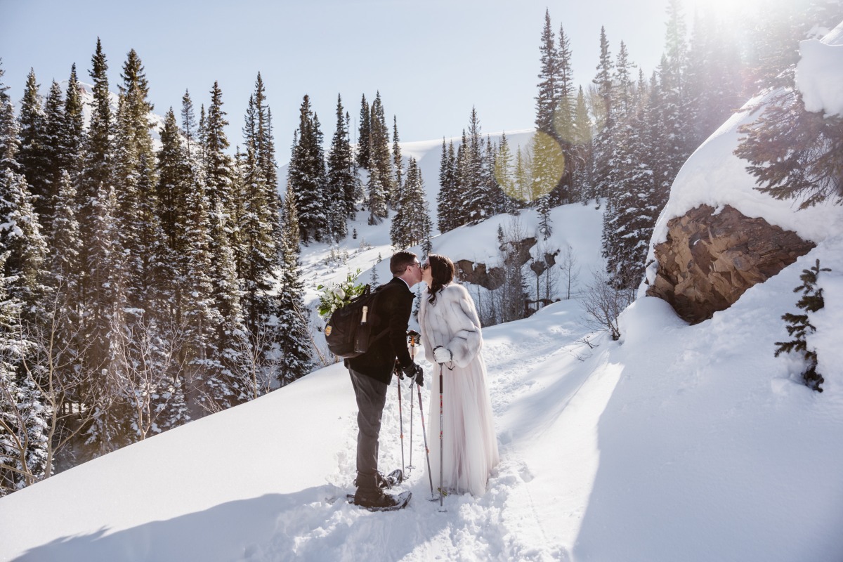 Couple sharing a kiss in a snowy mountain wedding ceremony