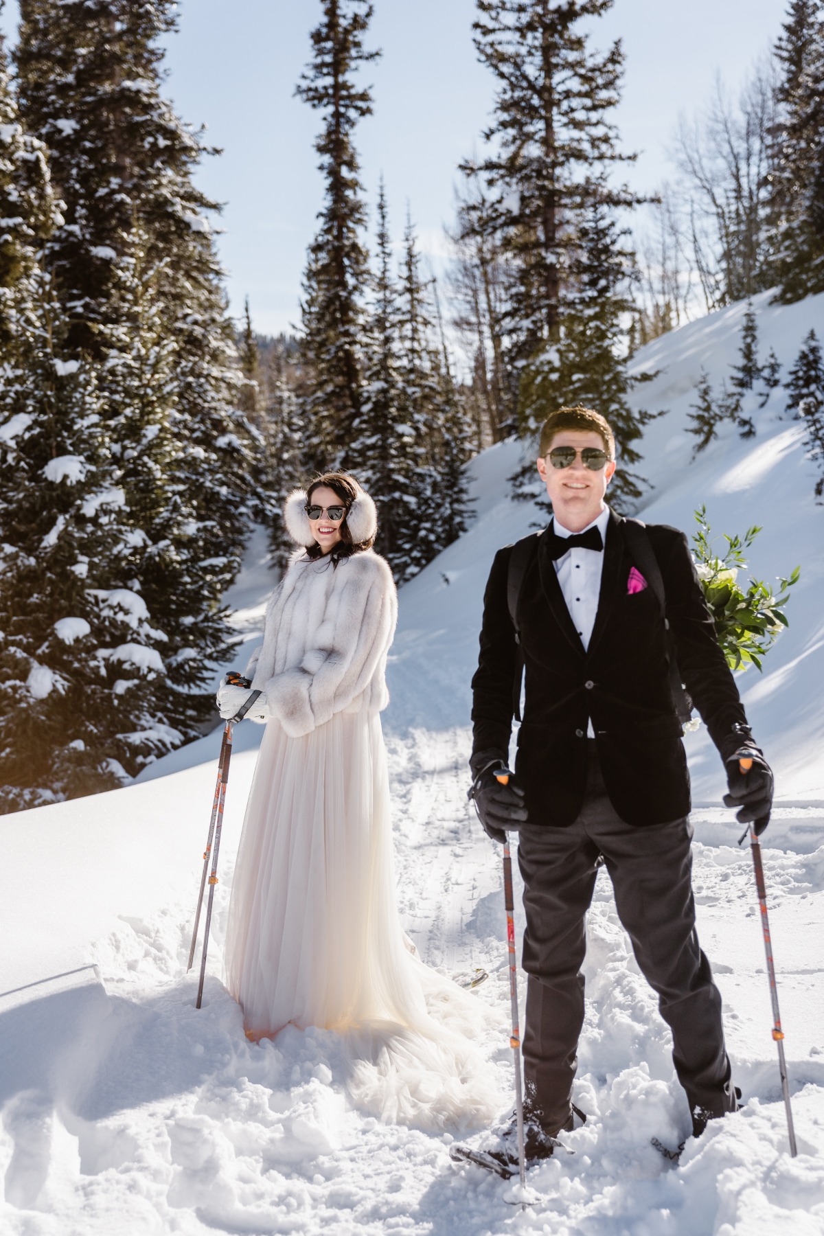 Bride and groom in wedding attire standing in snowy winter landscape