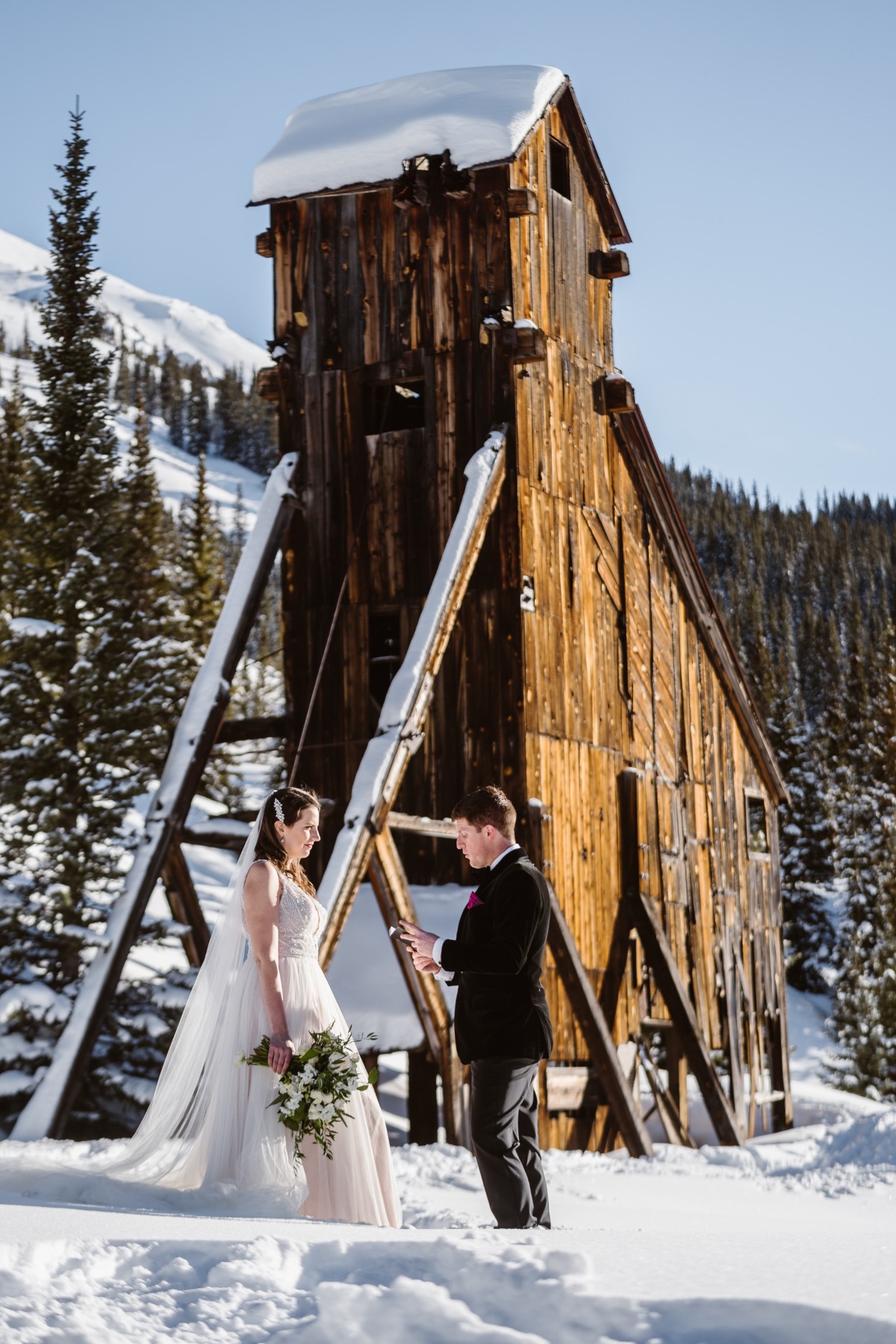Wedding vows in snow, couple in front of a wooden structure