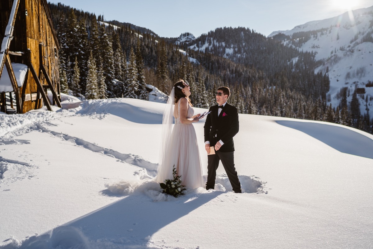 A smiling couple enjoying their winter wedding in a snowy mountain setting