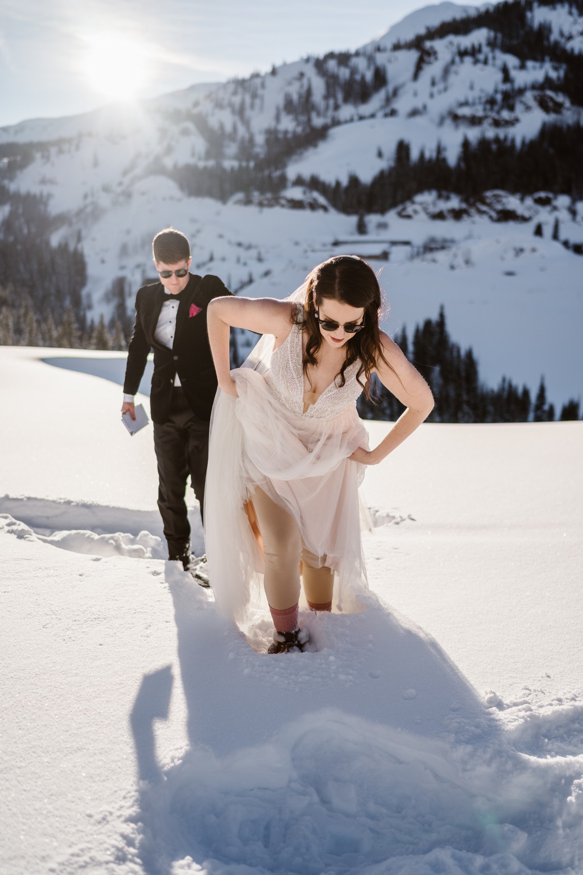A bride and groom walking through deep snow in a winter wonderland