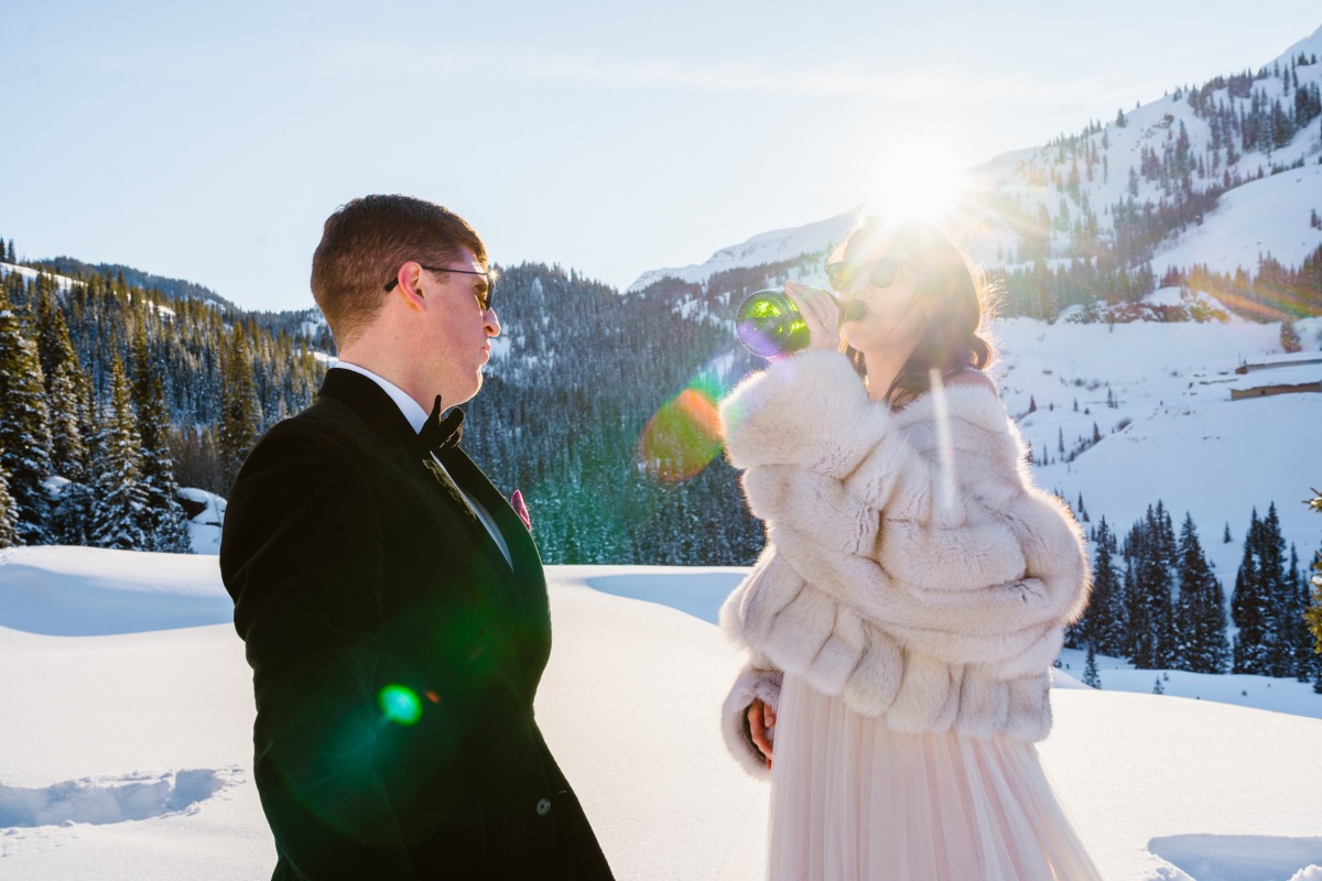 Bride and groom enjoying champagne in the snowy mountain scenery