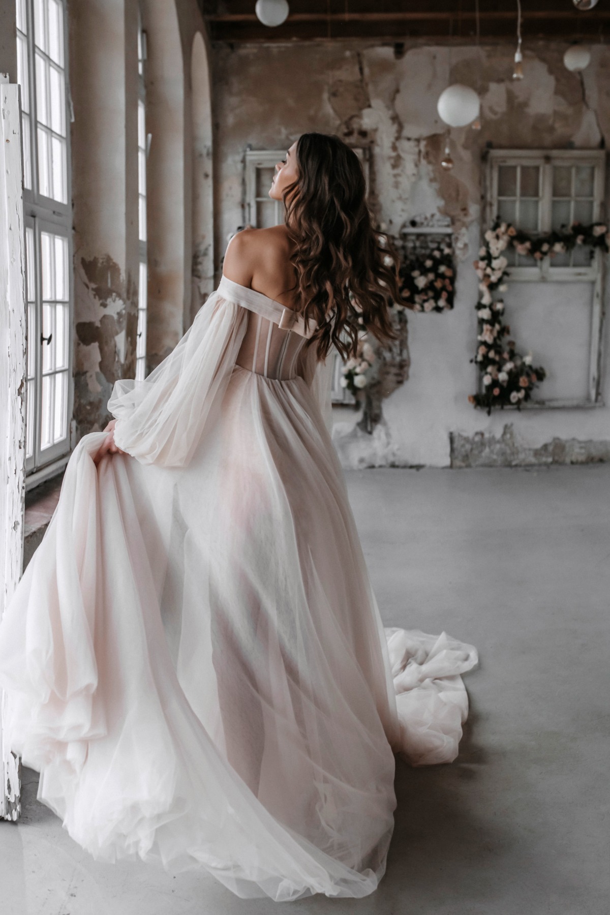 Elegant bride in a flowing wedding dress near a window