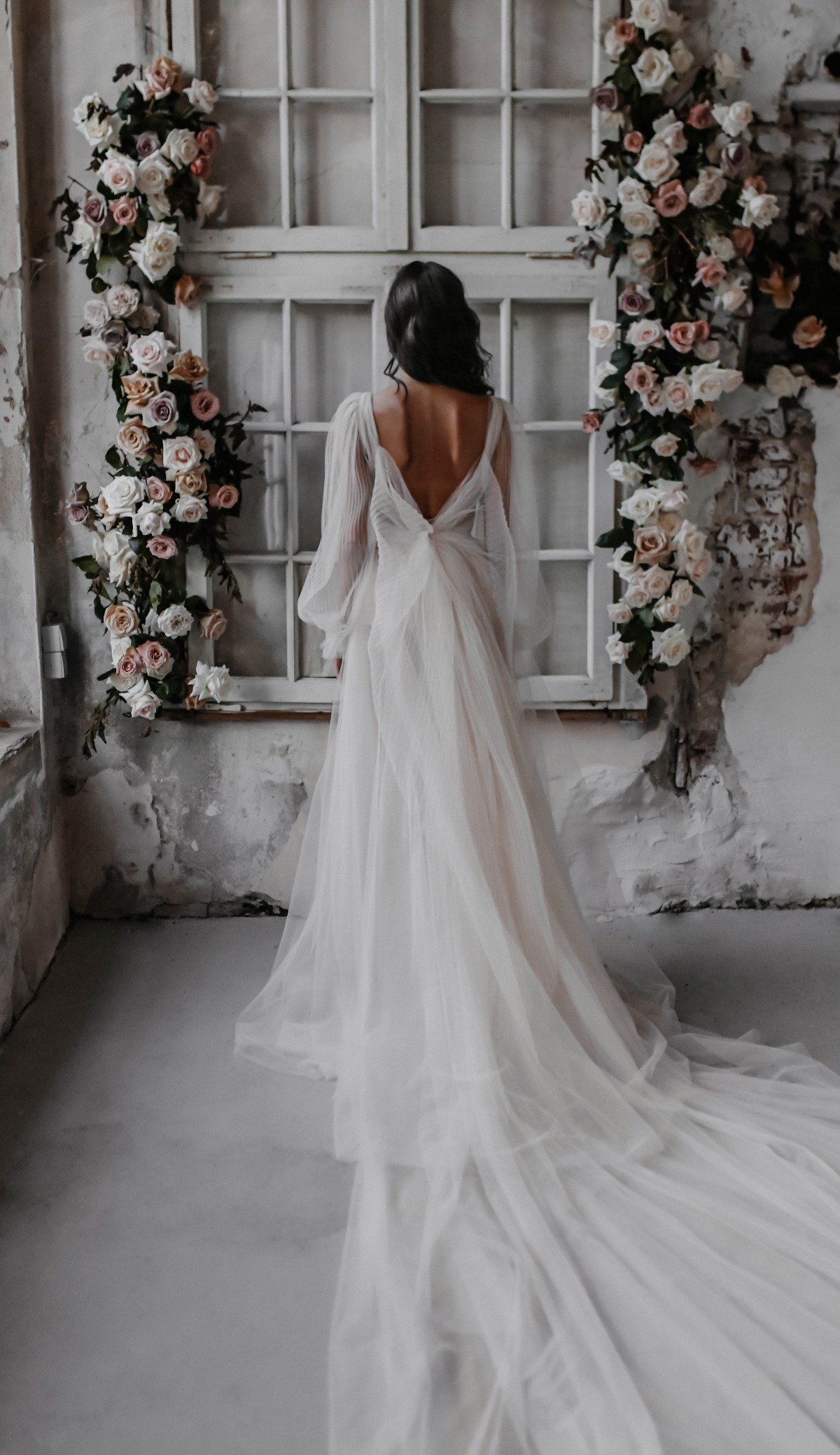 Bride in a stunning wedding dress with floral decorations near a window