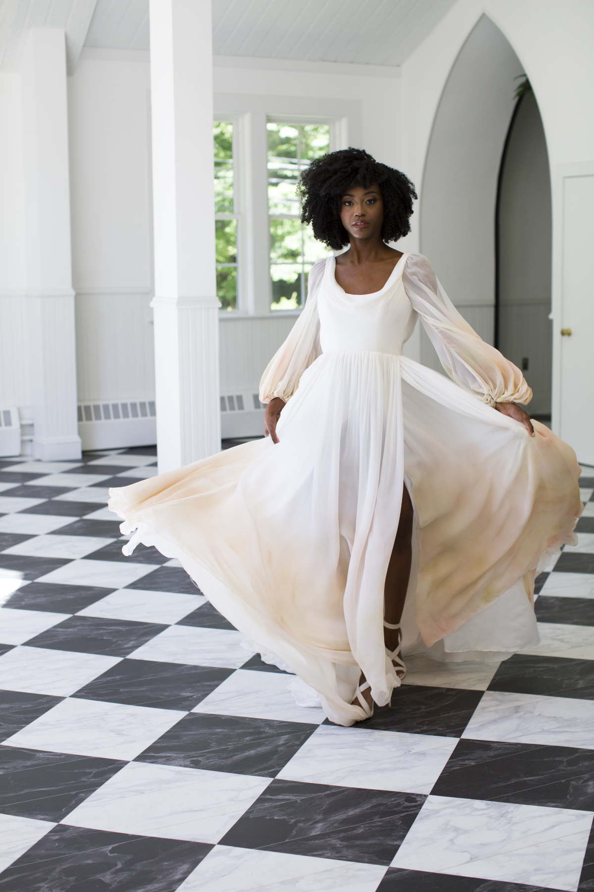 Elegant bride in a flowing white dress dances joyfully with soft light