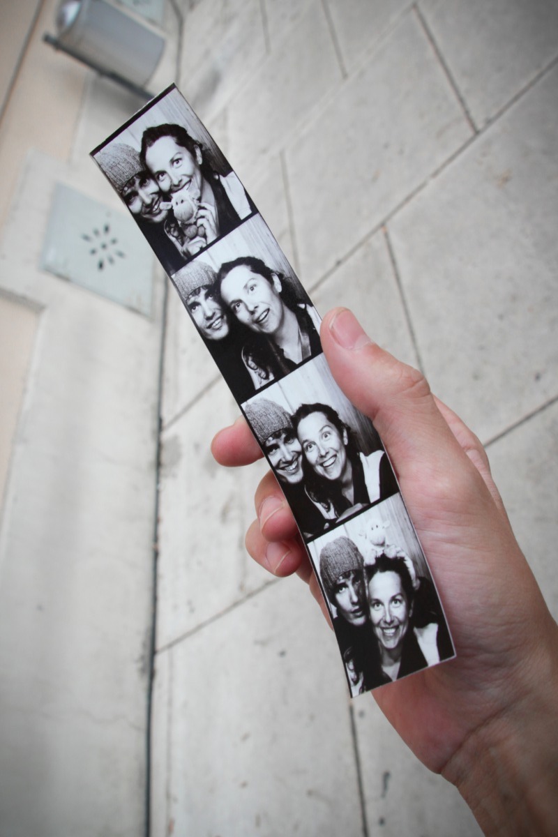 A hand holding a strip of black and white photobooth pictures