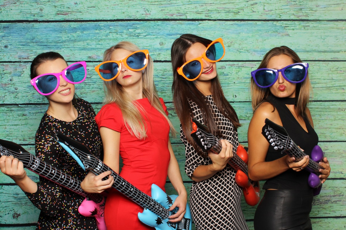 Four women in sunglasses posing with inflatable guitars