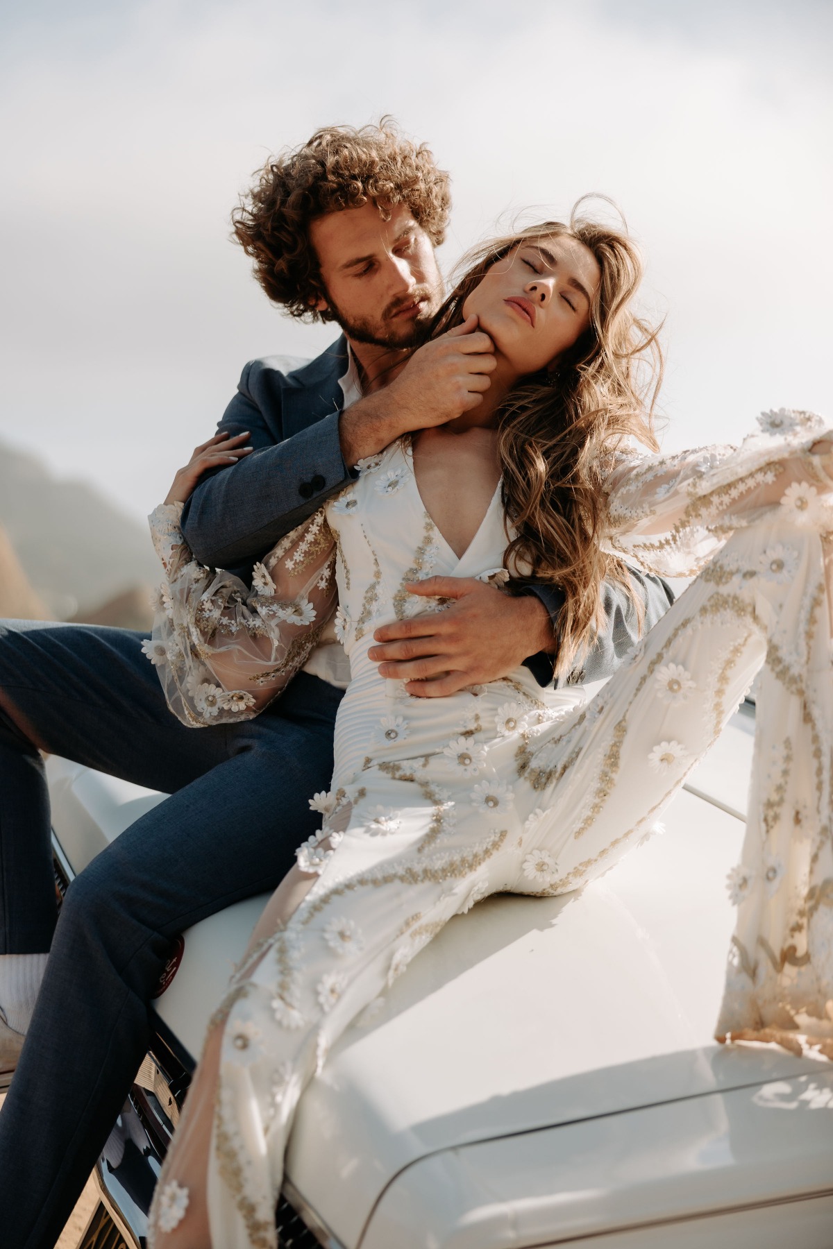 Romantic couple embraces on a vintage car, wedding photo shoot