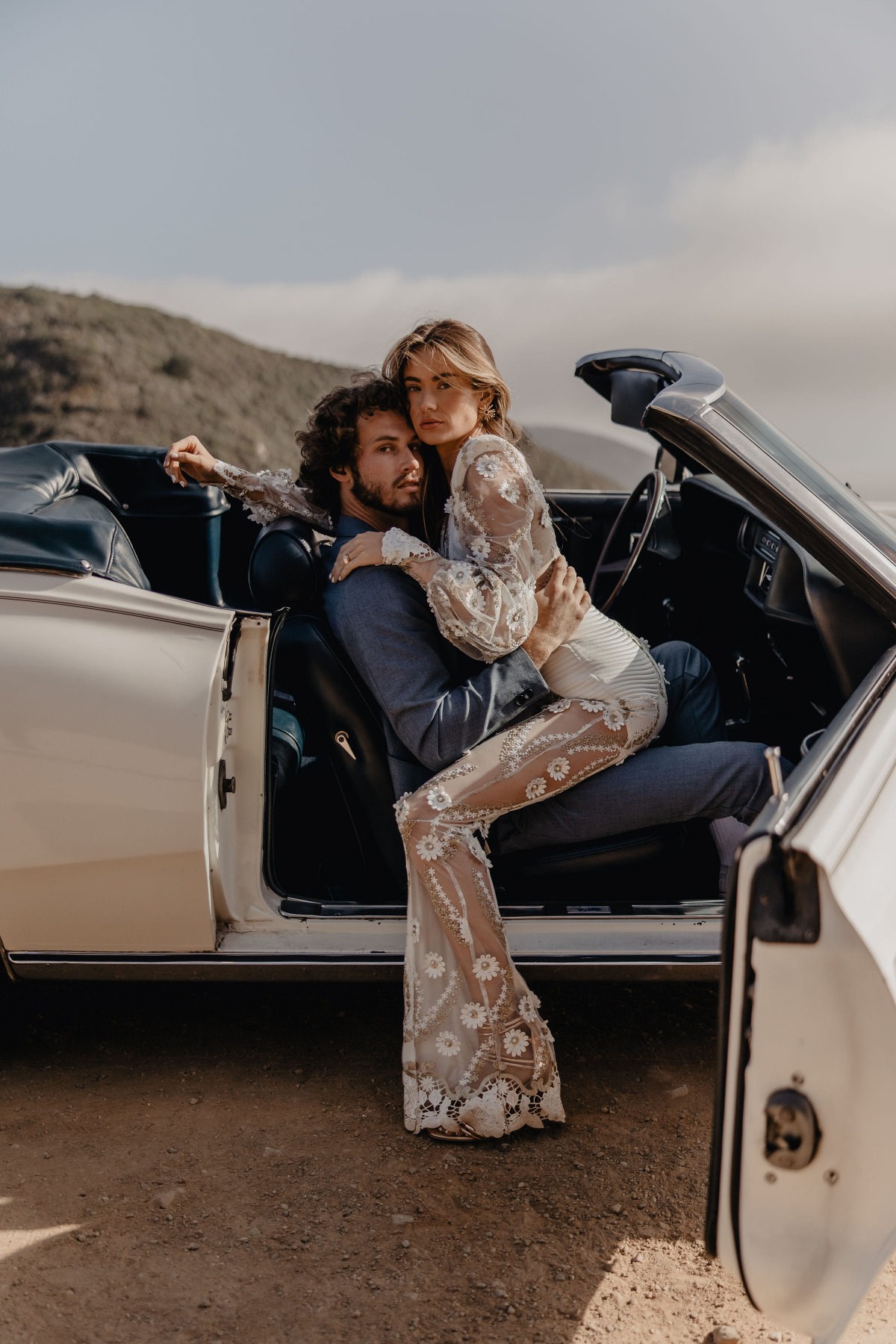 Romantic couple in vintage car posing for stylish wedding photo