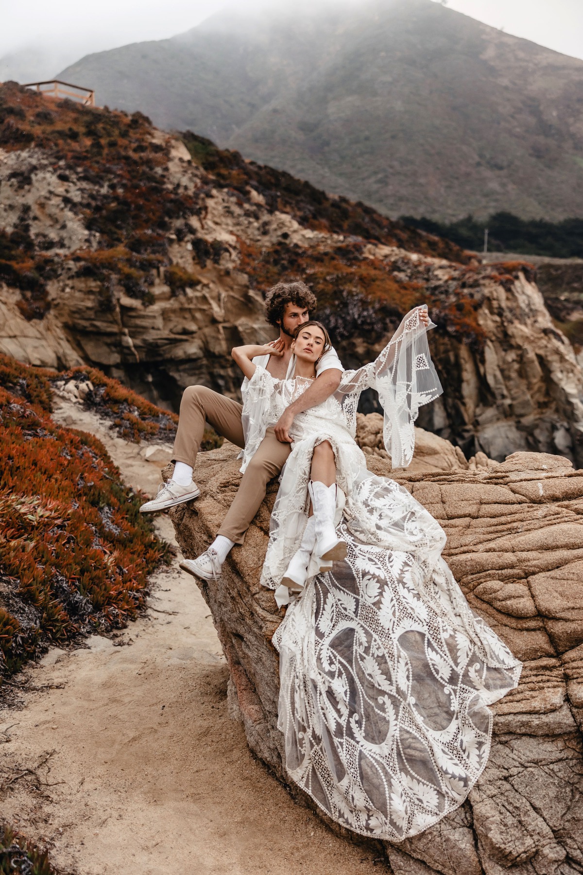 Romantic couple on a rock by the coast enjoying a misty day