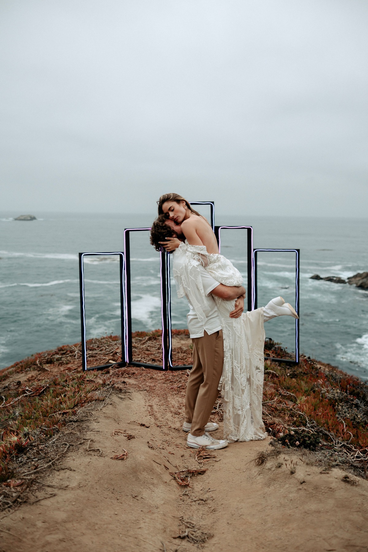 A couple embracing on a cliff with the ocean in the background