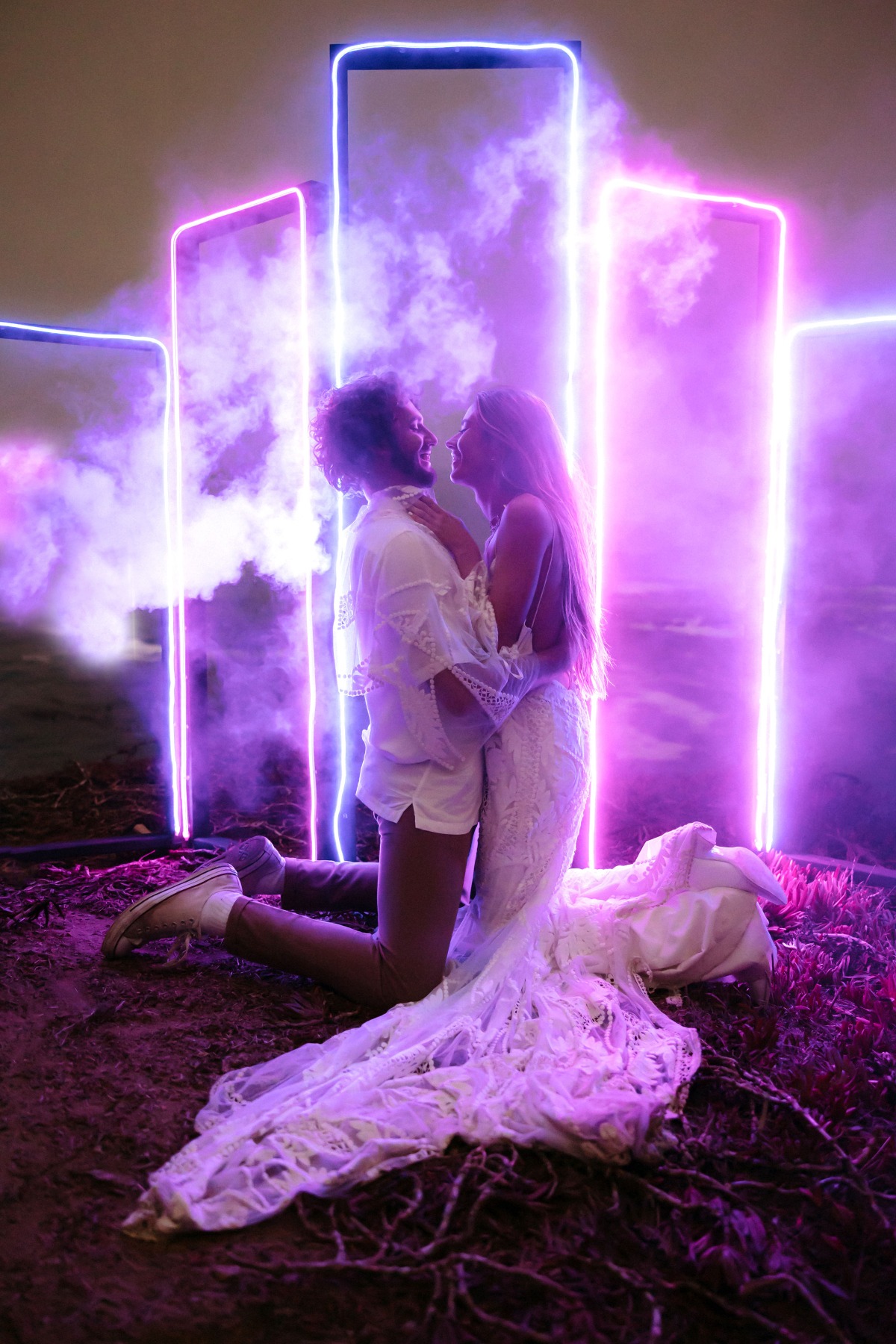 Romantic wedding couple embracing with neon light backdrop and smoke