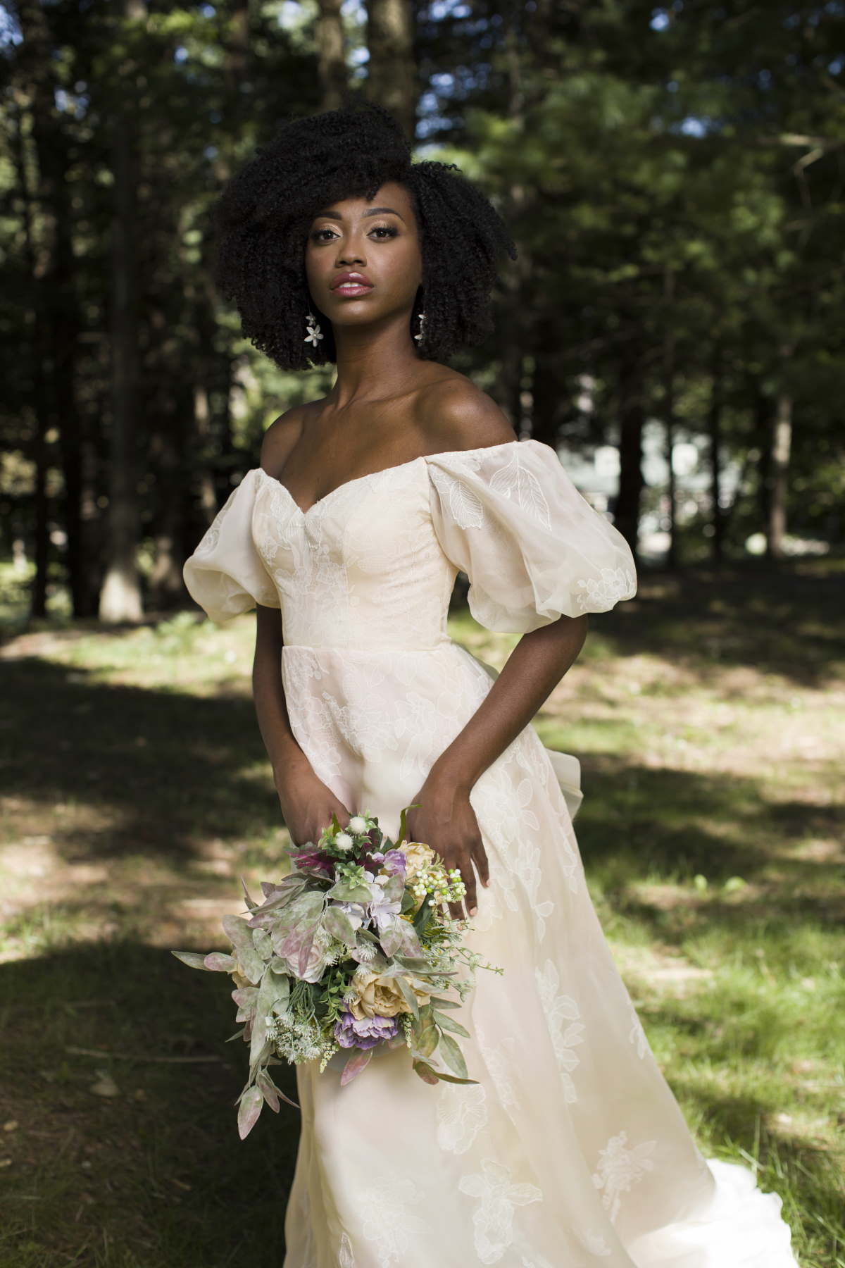 Elegant bride in off-shoulder dress with bouquet in nature