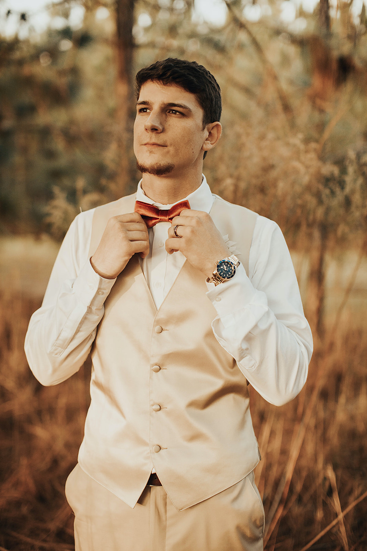 Handsome groom adjusting his bow tie, ready for his wedding day