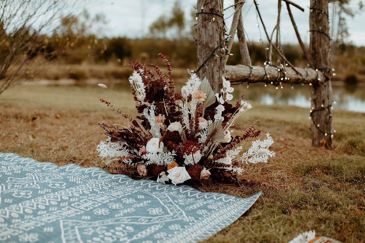 Floral arrangement on a blanket in a outdoor setting with wooden structure