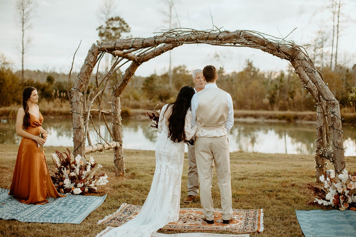 Outdoor wedding ceremony with couple under wooden archway