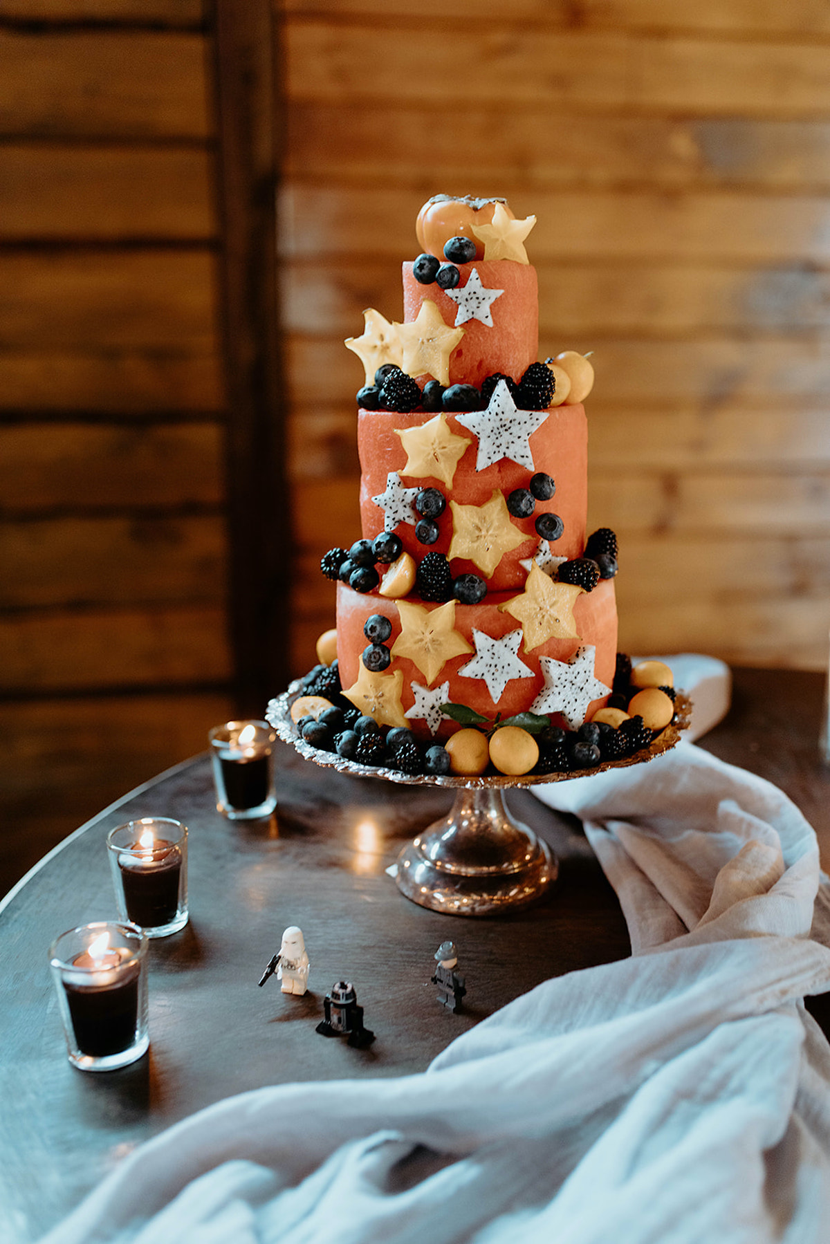 A vibrant orange tiered cake decorated with star fruits and berries