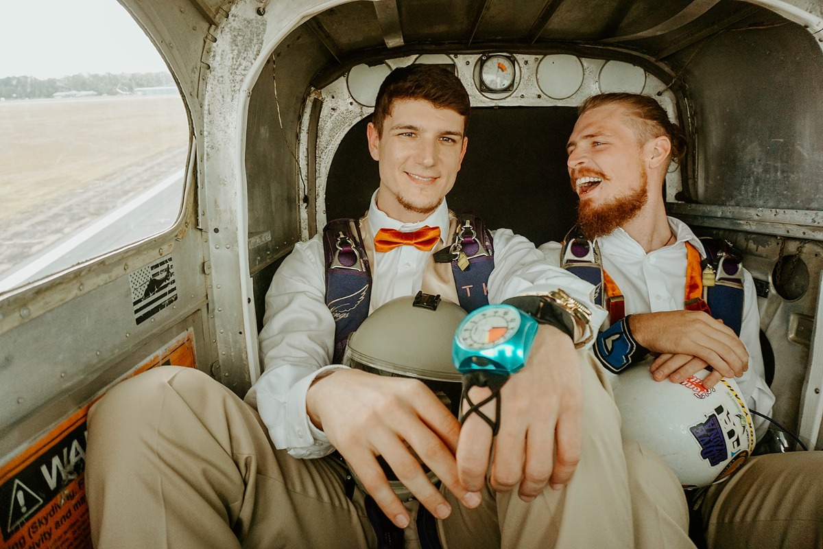 Two men in a plane ready for a skydive with excited expressions