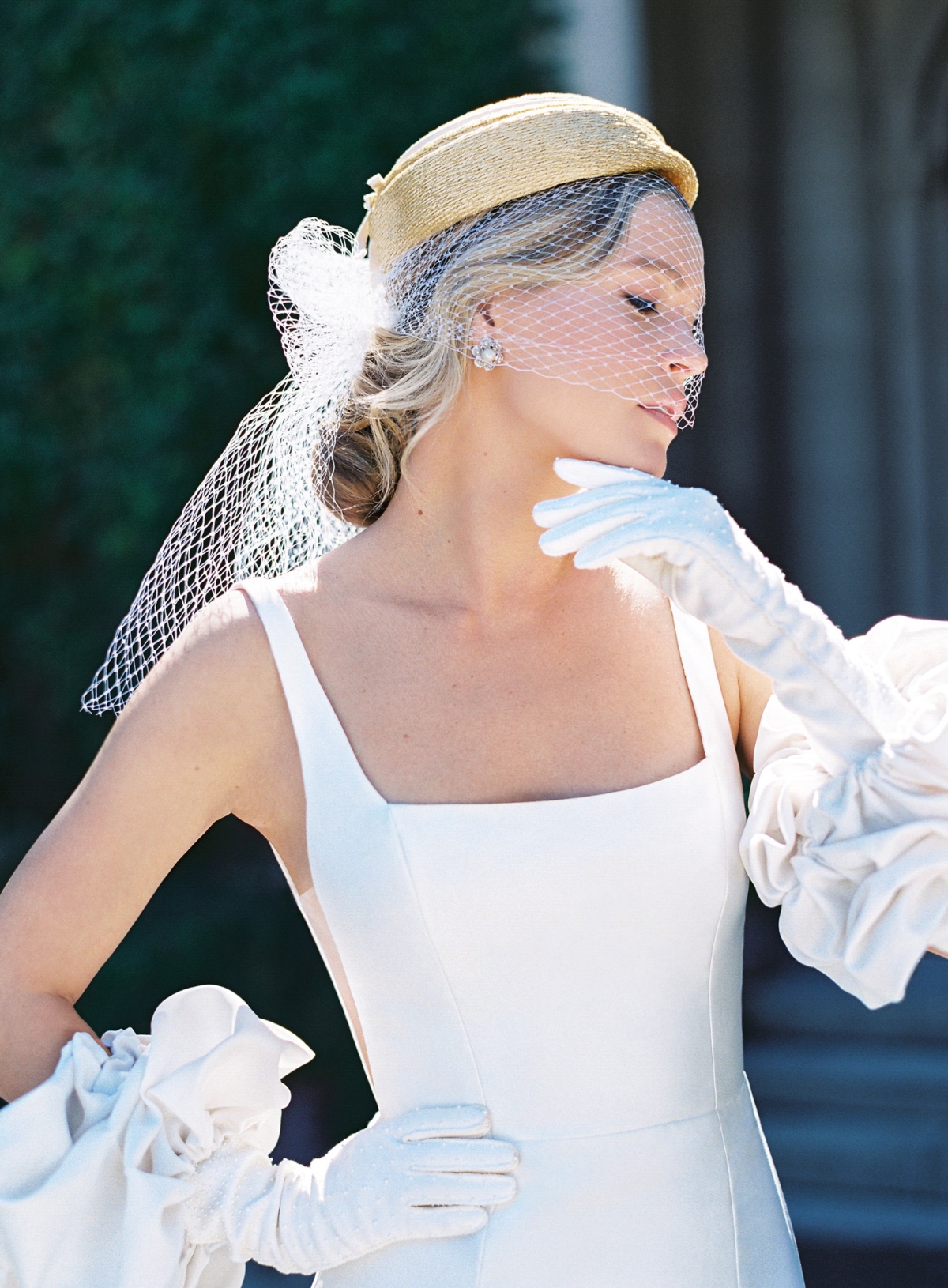 Elegant bride in a white dress and gloves, veil and hat