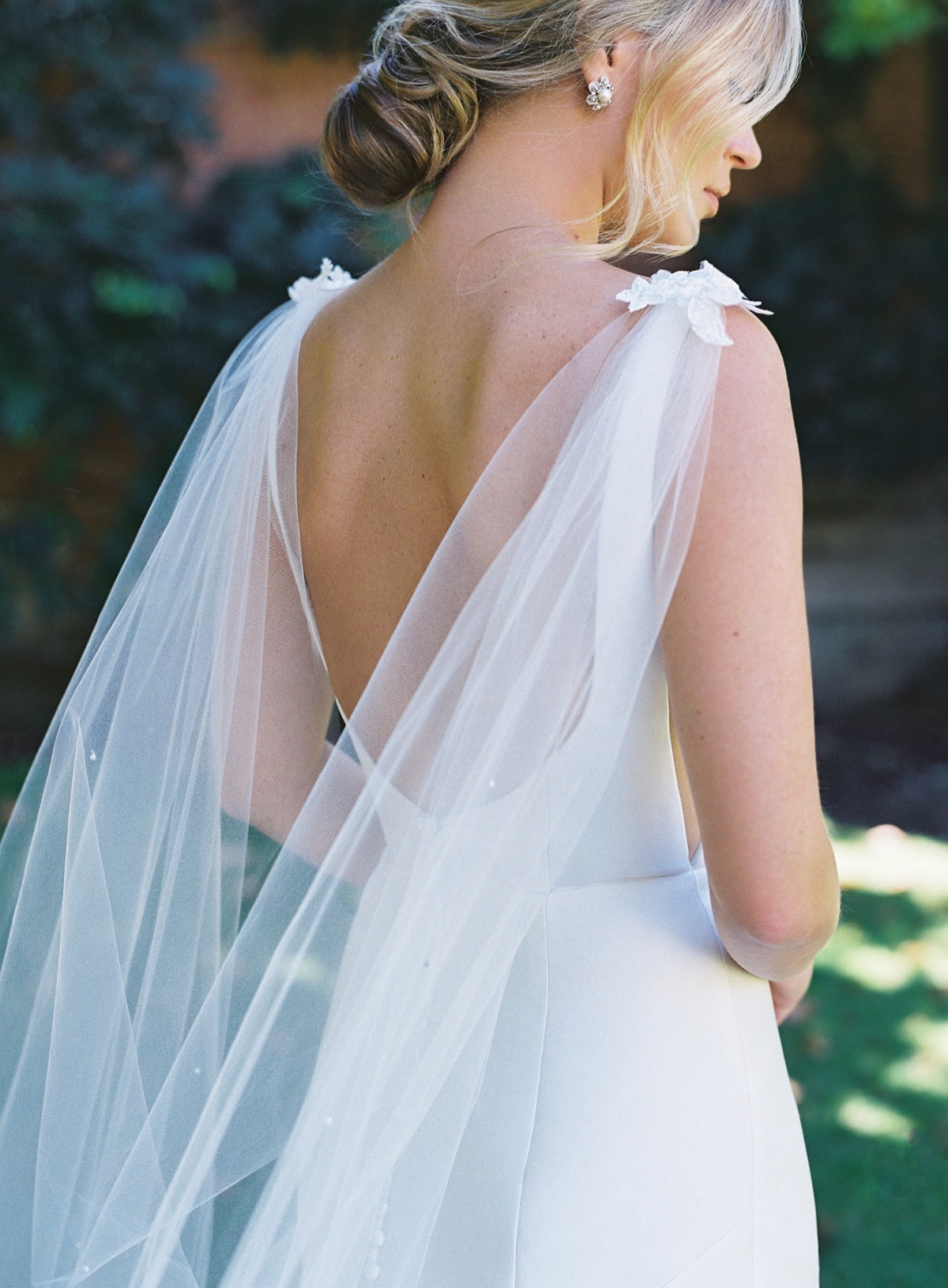 Elegant bride in a backless wedding dress with a sheer veil