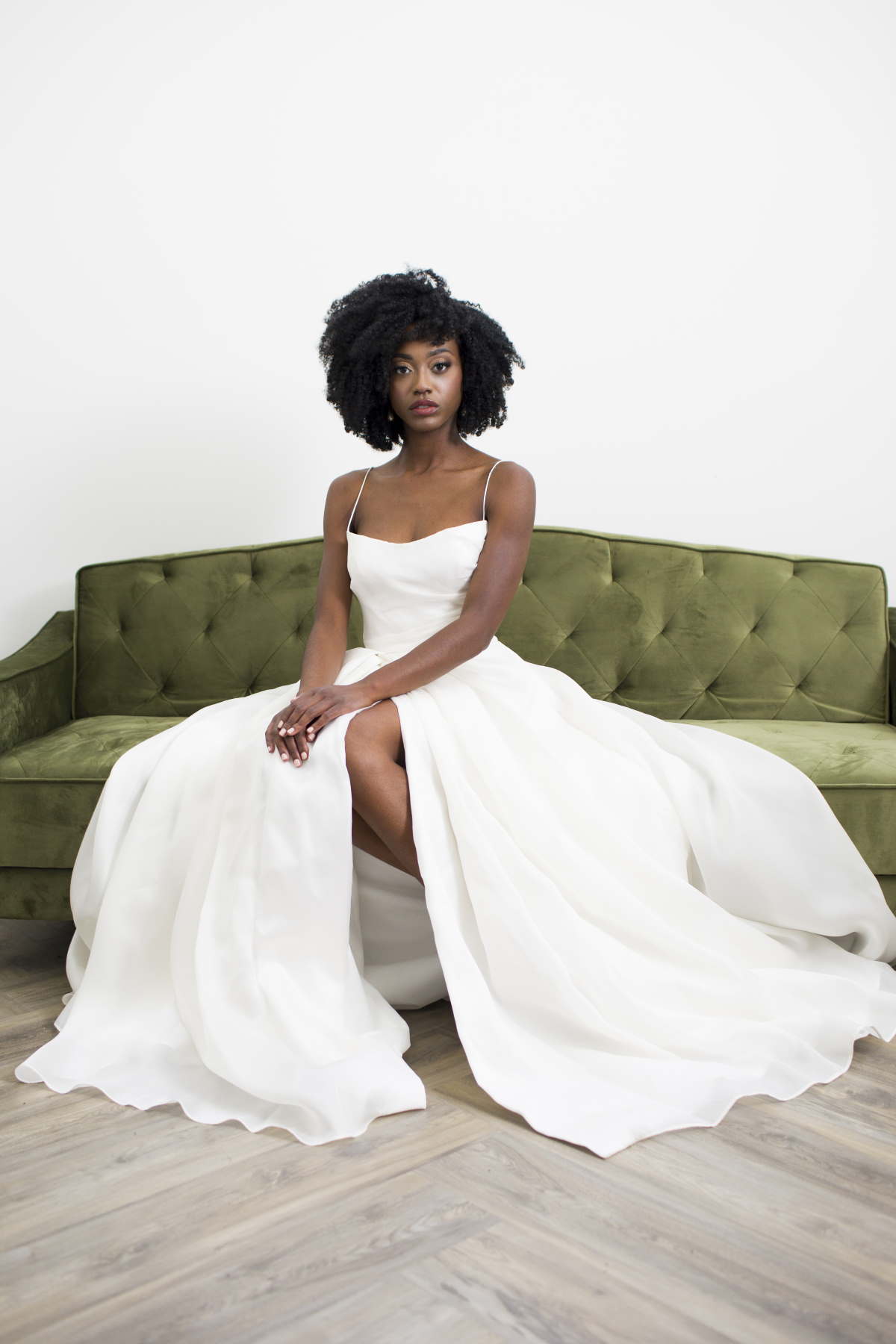 Elegant Black Bride in a White Wedding Dress on a Green Couch