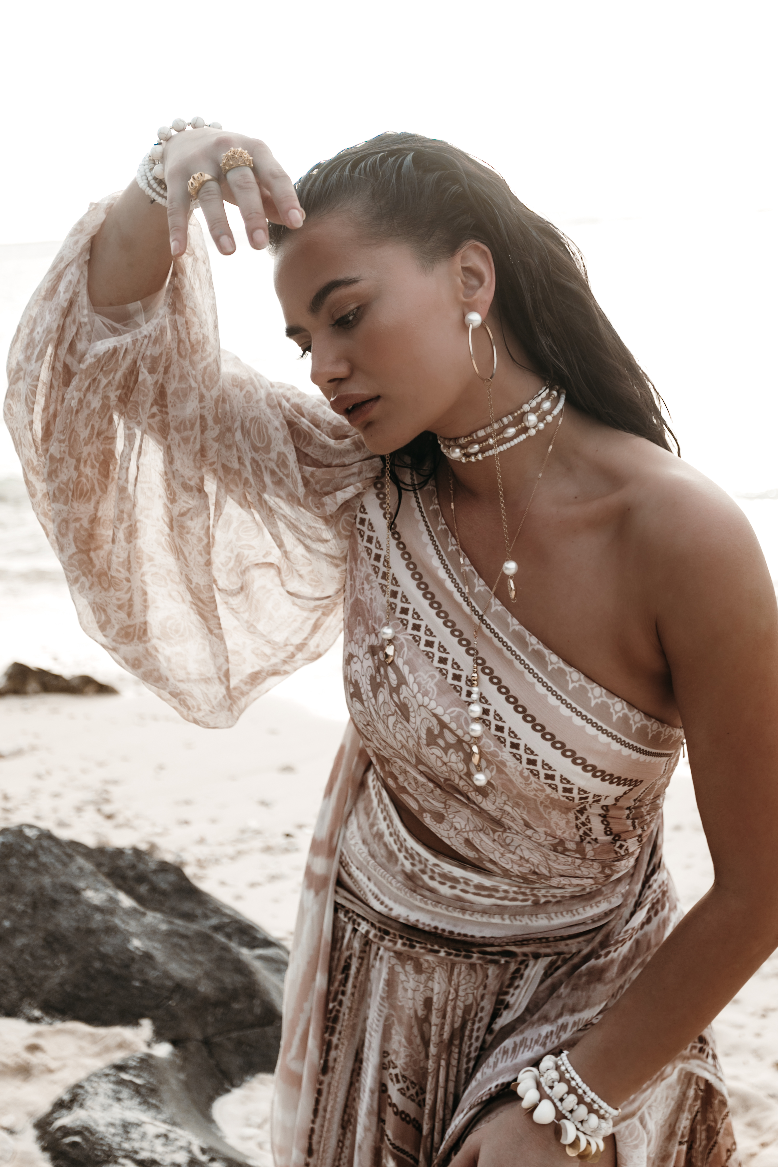 Woman on beach wearing jewelry and one shoulder dress