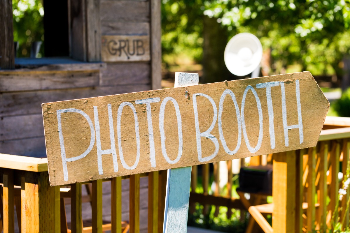 Wooden photo booth sign pointing towards the photo booth location