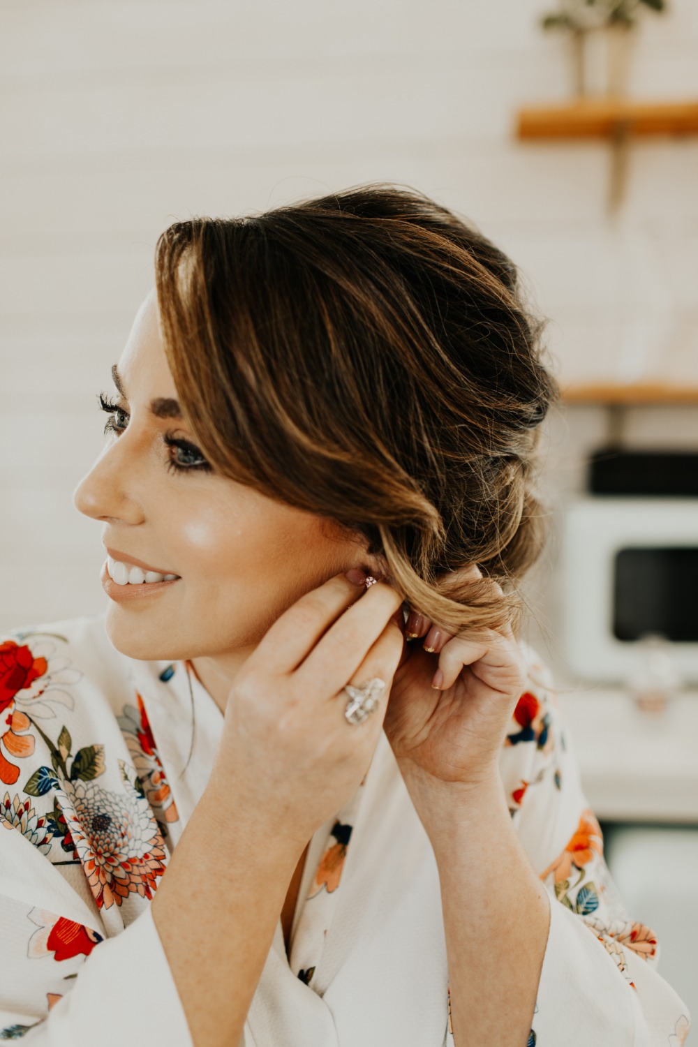 Bride puts on earrings, smiling, preparing for her wedding