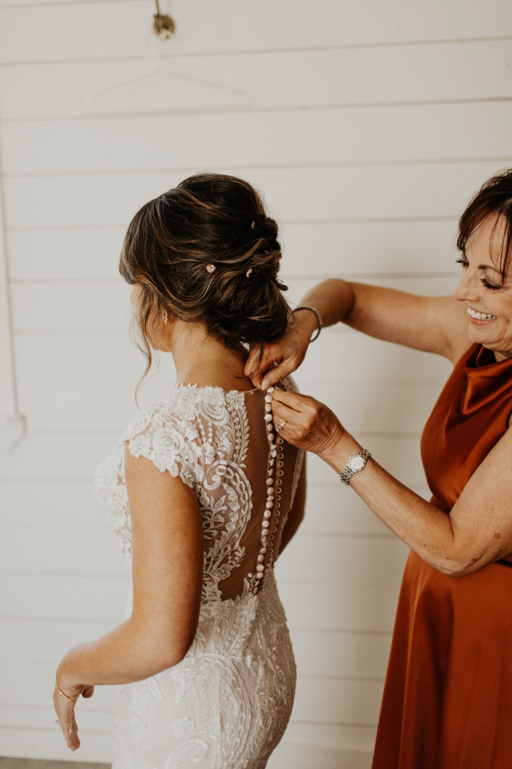 Mother of the bride helping fasten wedding dress buttons