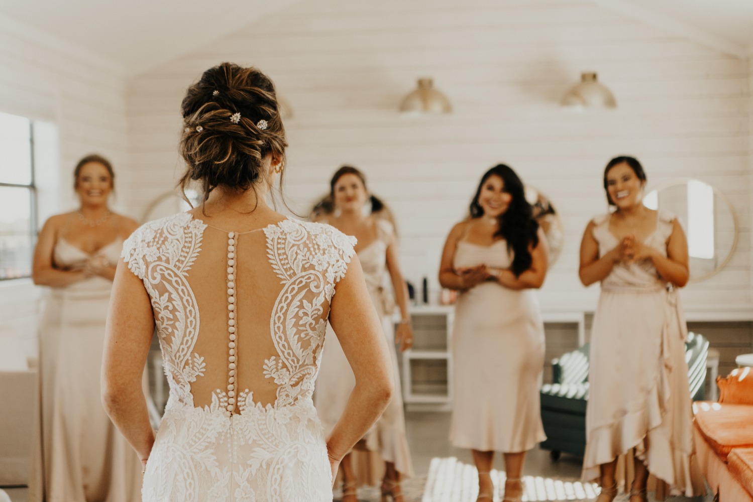 Bride in a stunning dress with her bridesmaids watching with joy