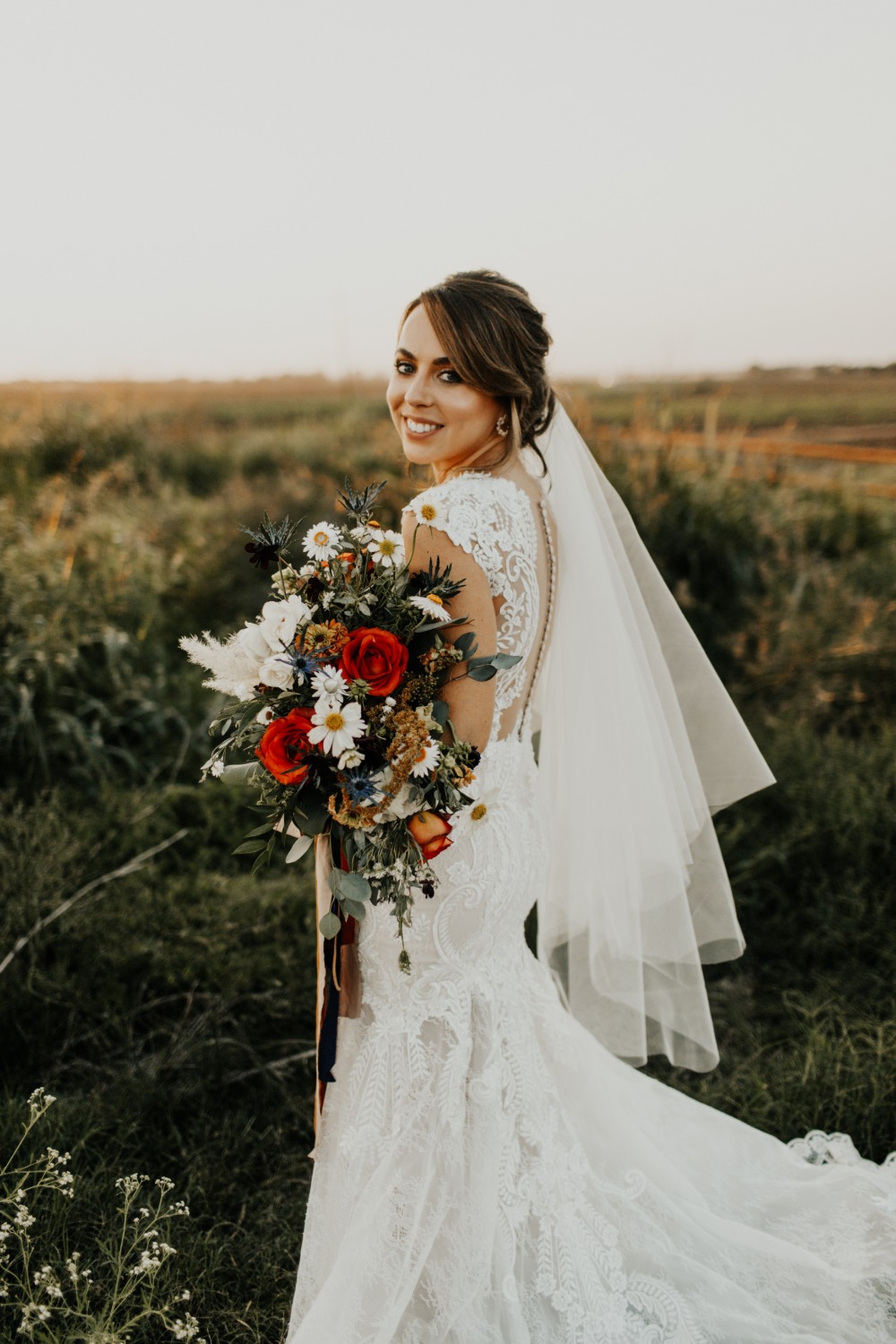 Happy bride in a lace dress, holding a colorful bouquet of flowers