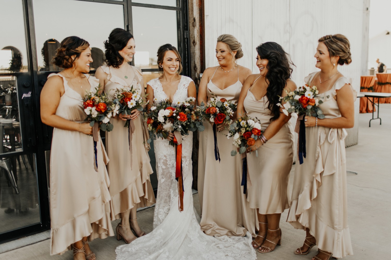 Bride with bridesmaids smiling, holding colorful bouquets