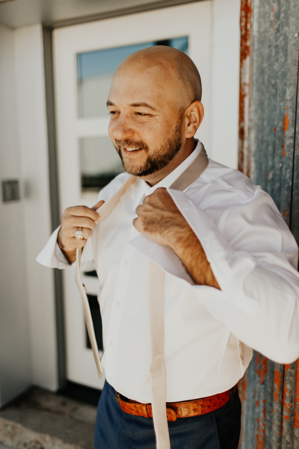 Groom adjusting his tie, getting ready for the wedding, smiling