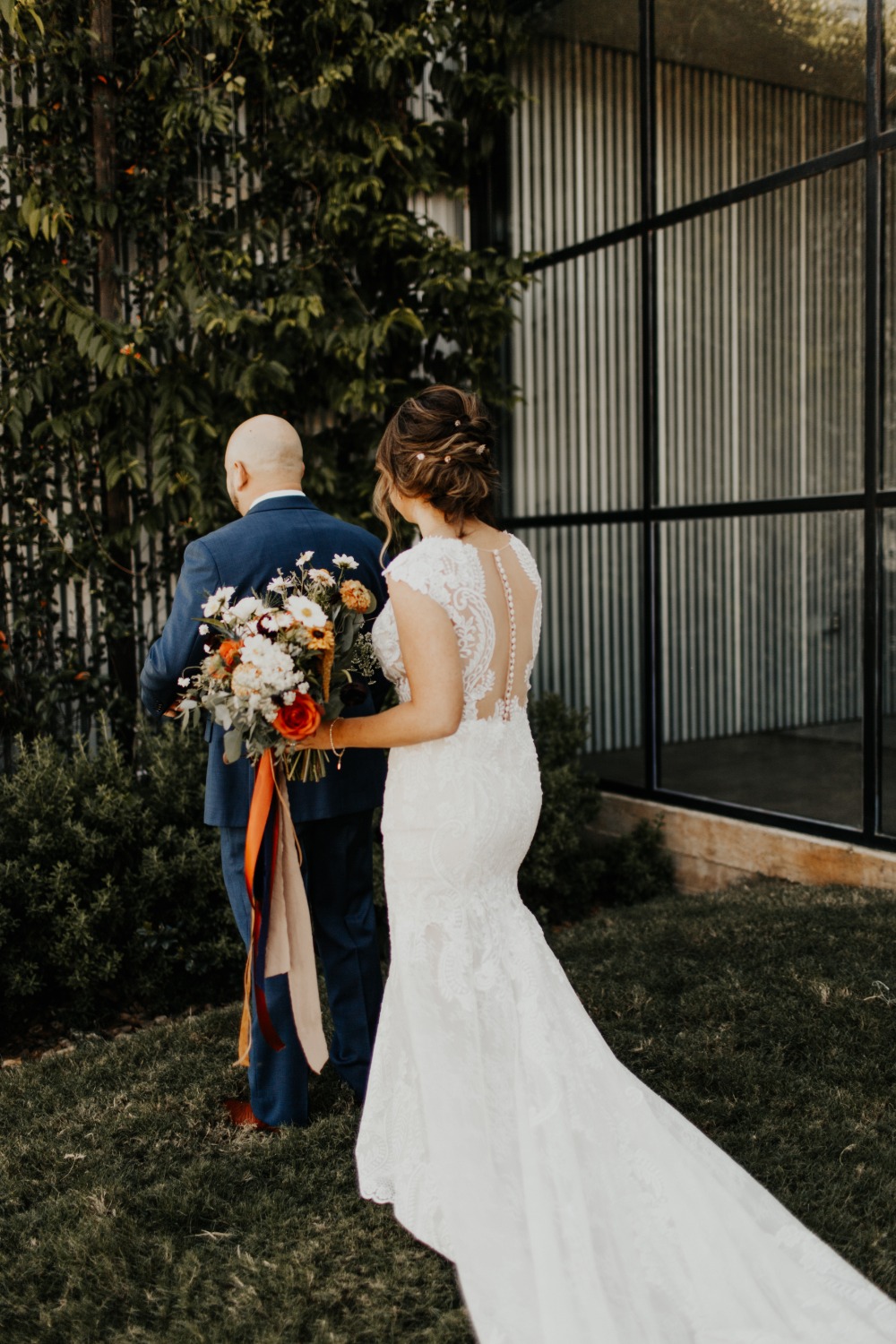 Bride and father walk towards the wedding ceremony in the garden