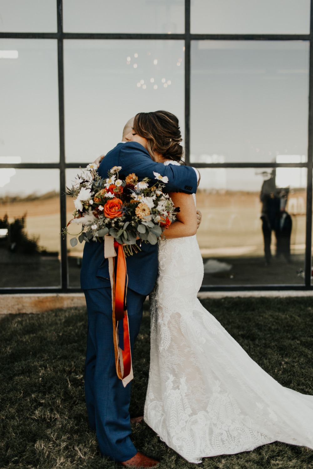 Bride and groom share a loving embrace on their wedding day with flowers