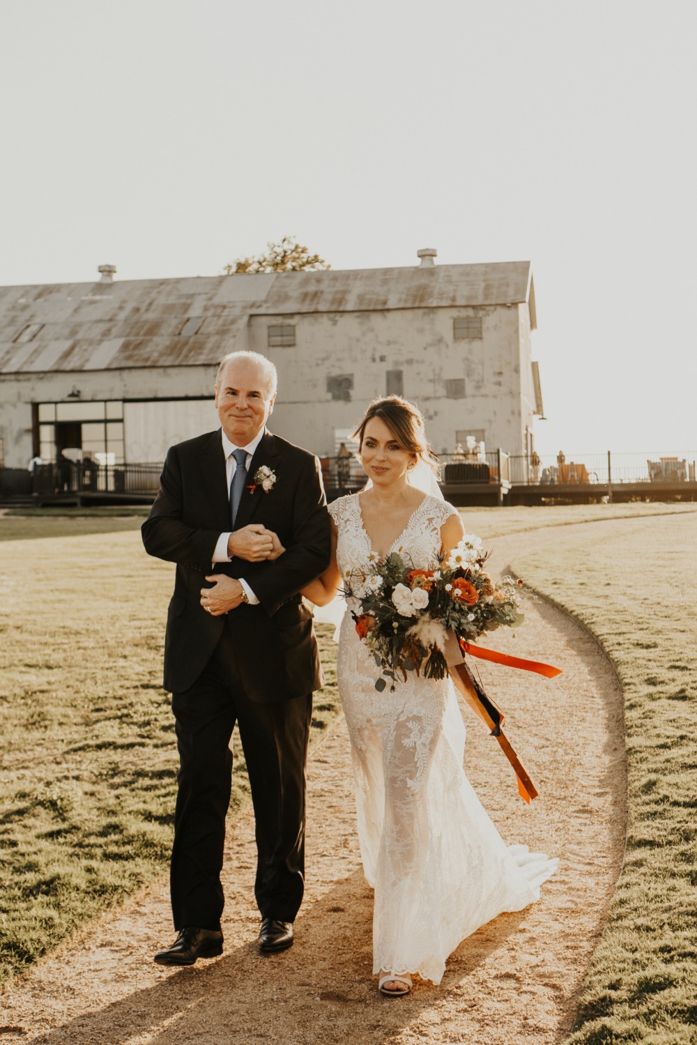 Bride walks down the aisle with her father at outdoor wedding