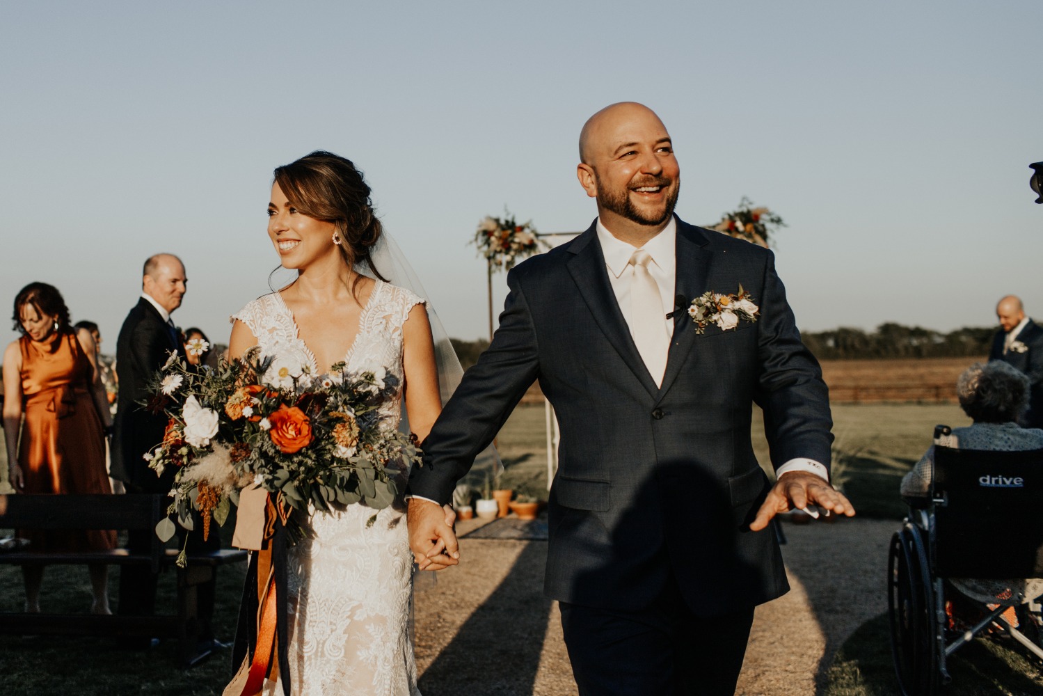 Newlyweds walk hand in hand after their outdoor wedding ceremony