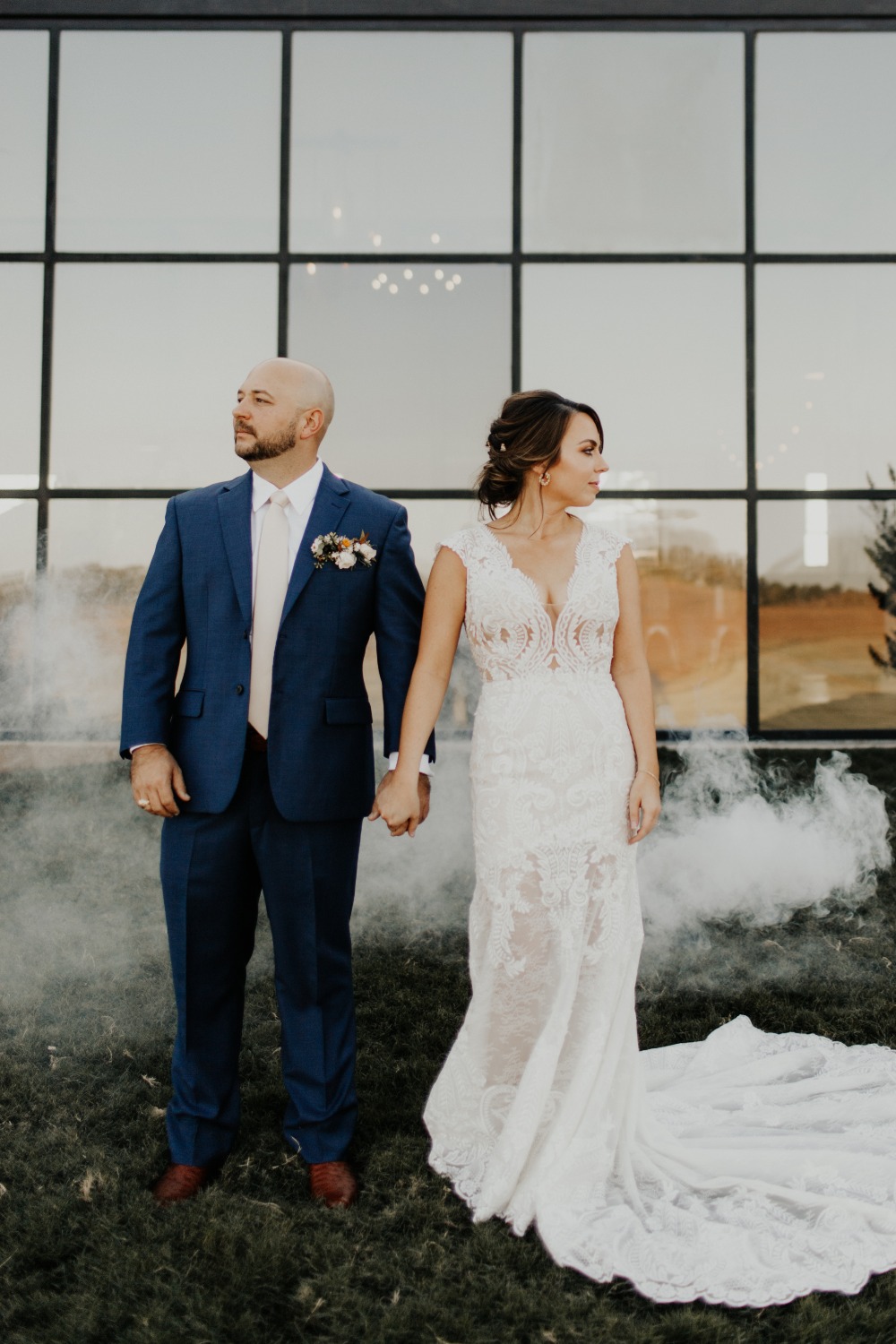 Wedding couple posing outdoors in front of a modern glass building