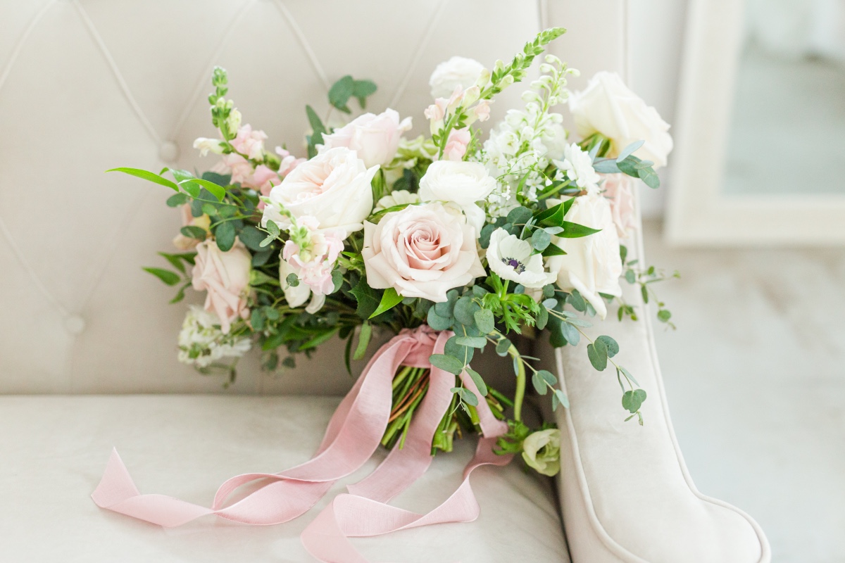 Elegant bouquet of roses and greenery with pink ribbon on a chair