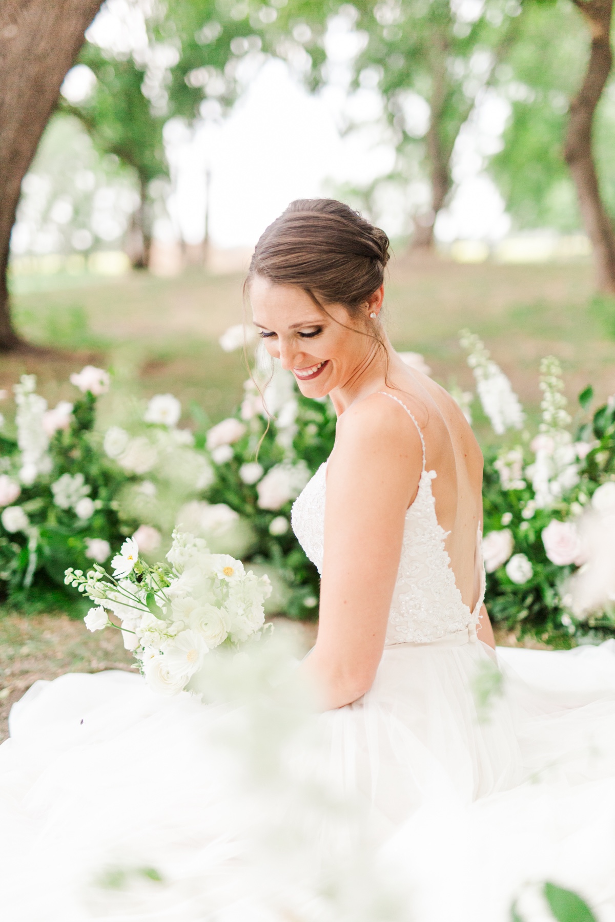Happy bride in a wedding dress smiles holding a bouquet of flowers
