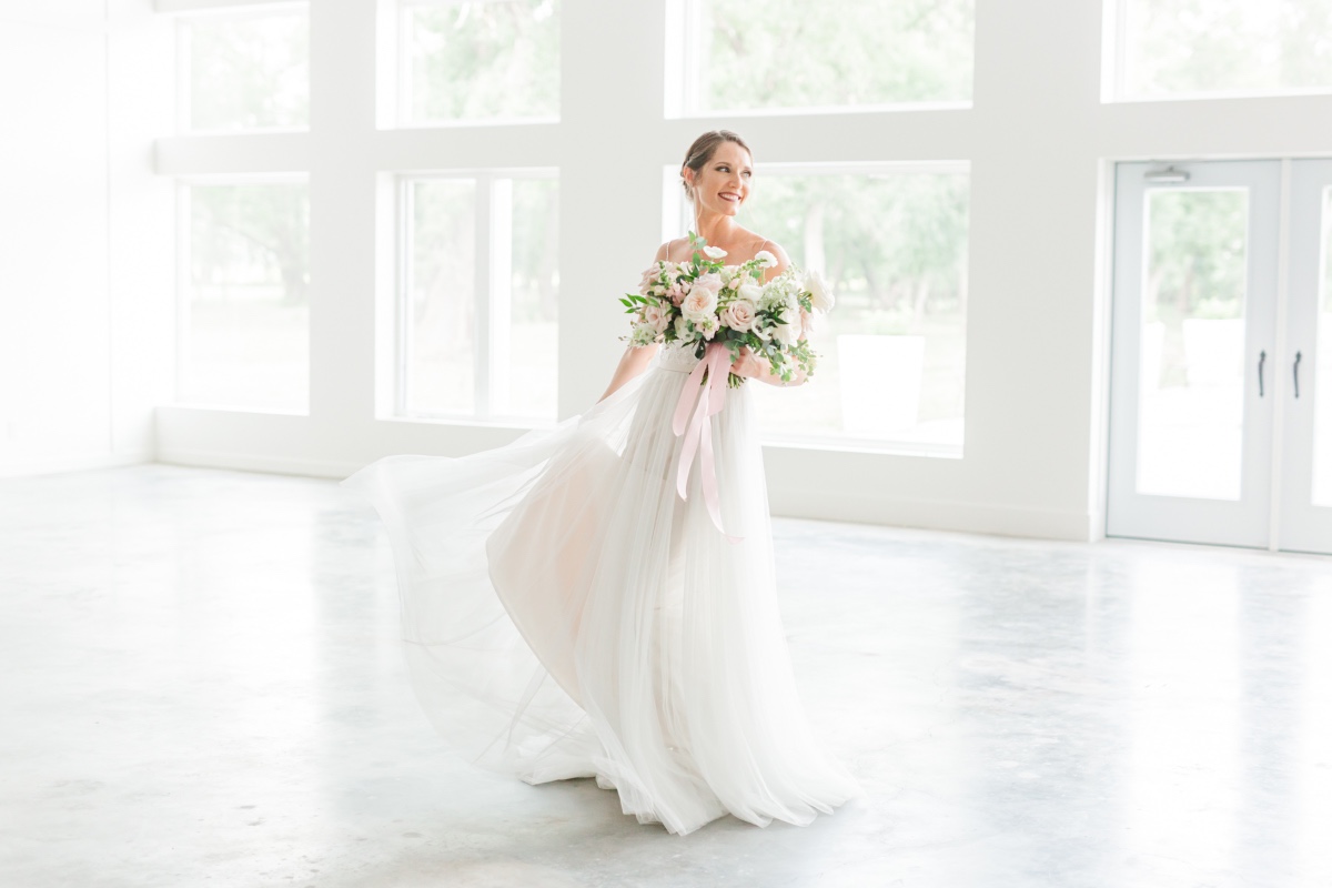 Happy bride in a flowing wedding dress holding a bouquet