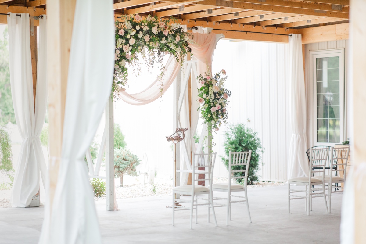 Wedding ceremony setting with floral decorations and white chairs