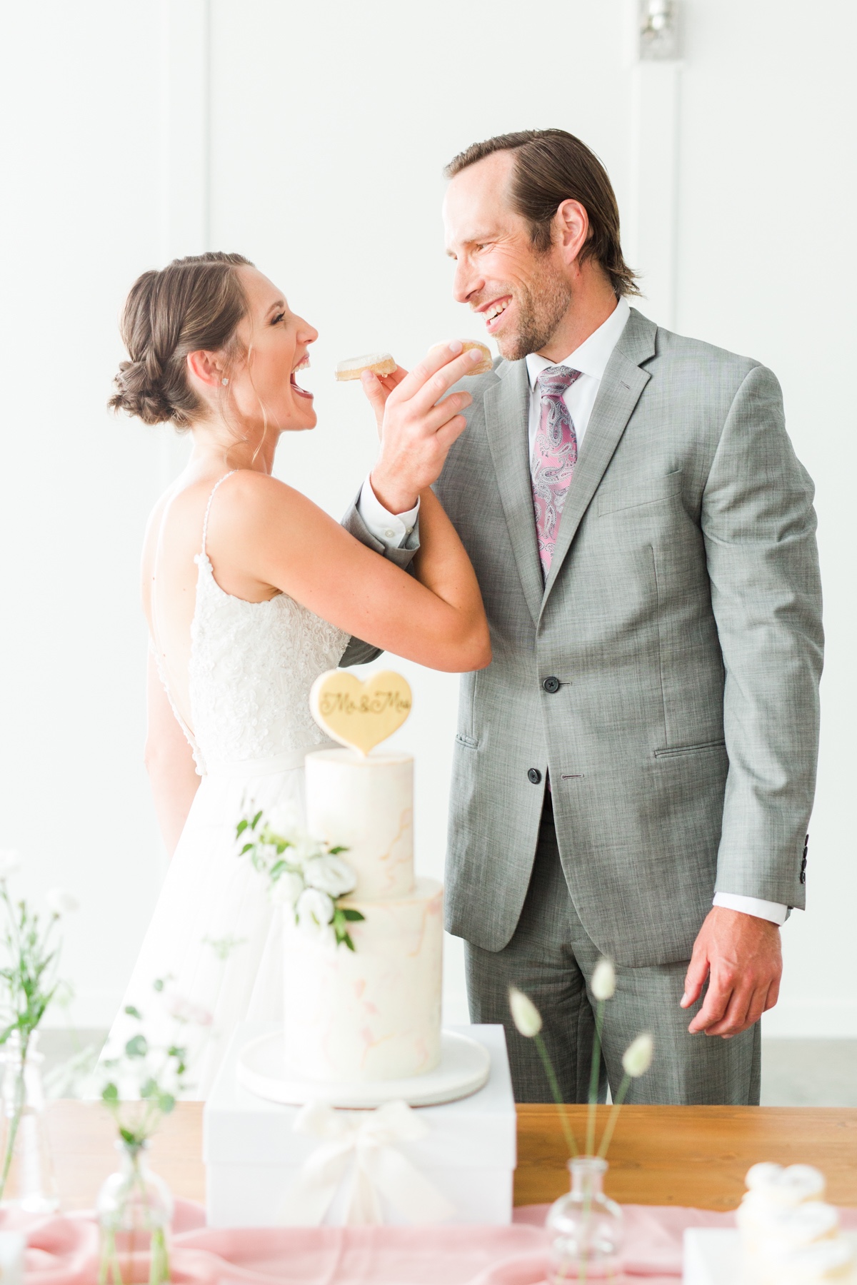 Happy couple feeding each other wedding cake, smiling joyfully