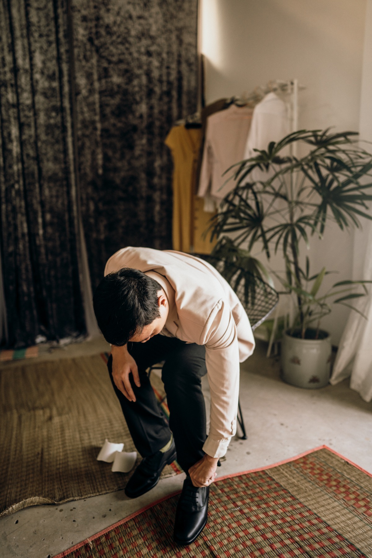 Man in shirt and pants fastening dress shoes at home