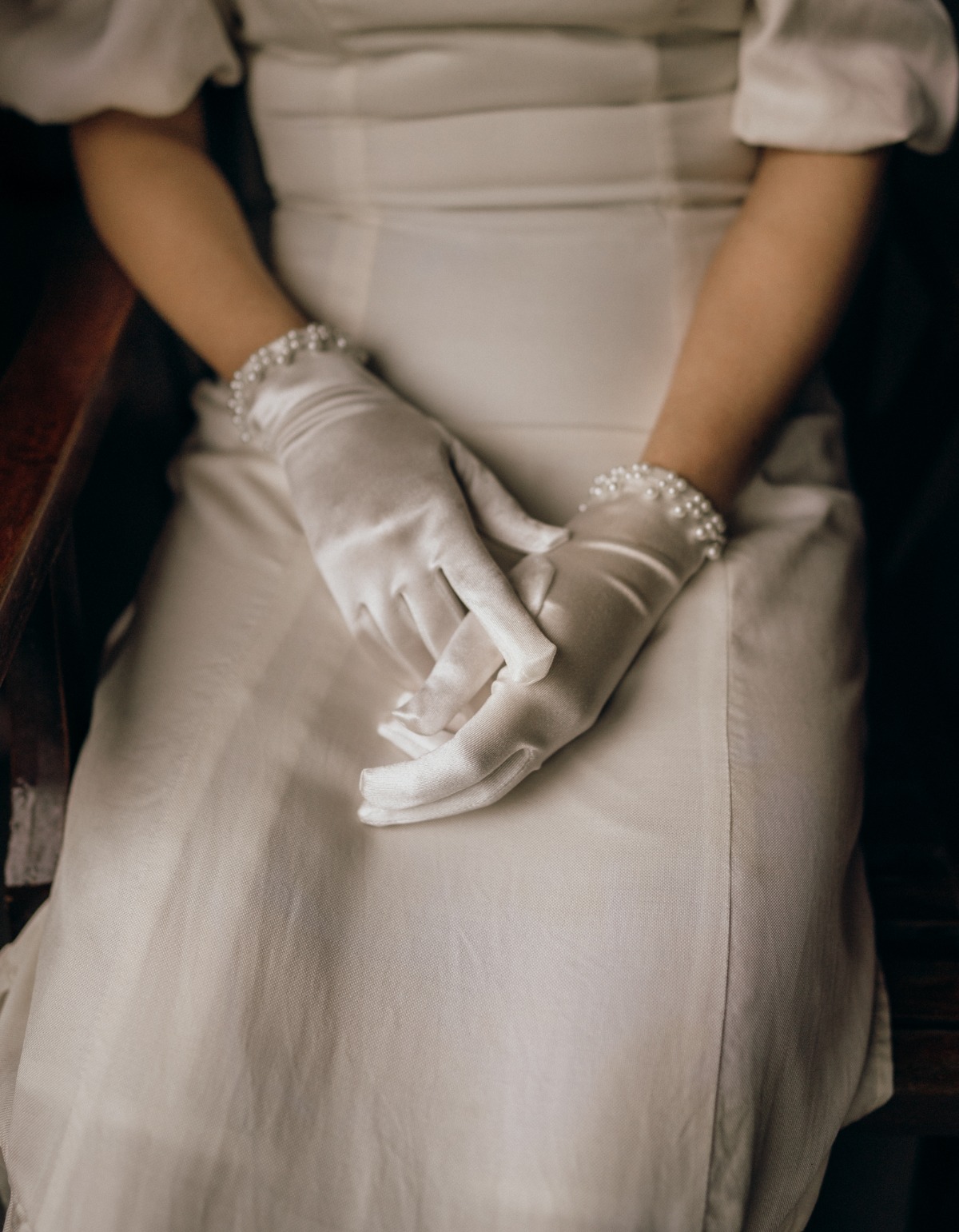 Woman in white dress and gloves with pearl bracelets