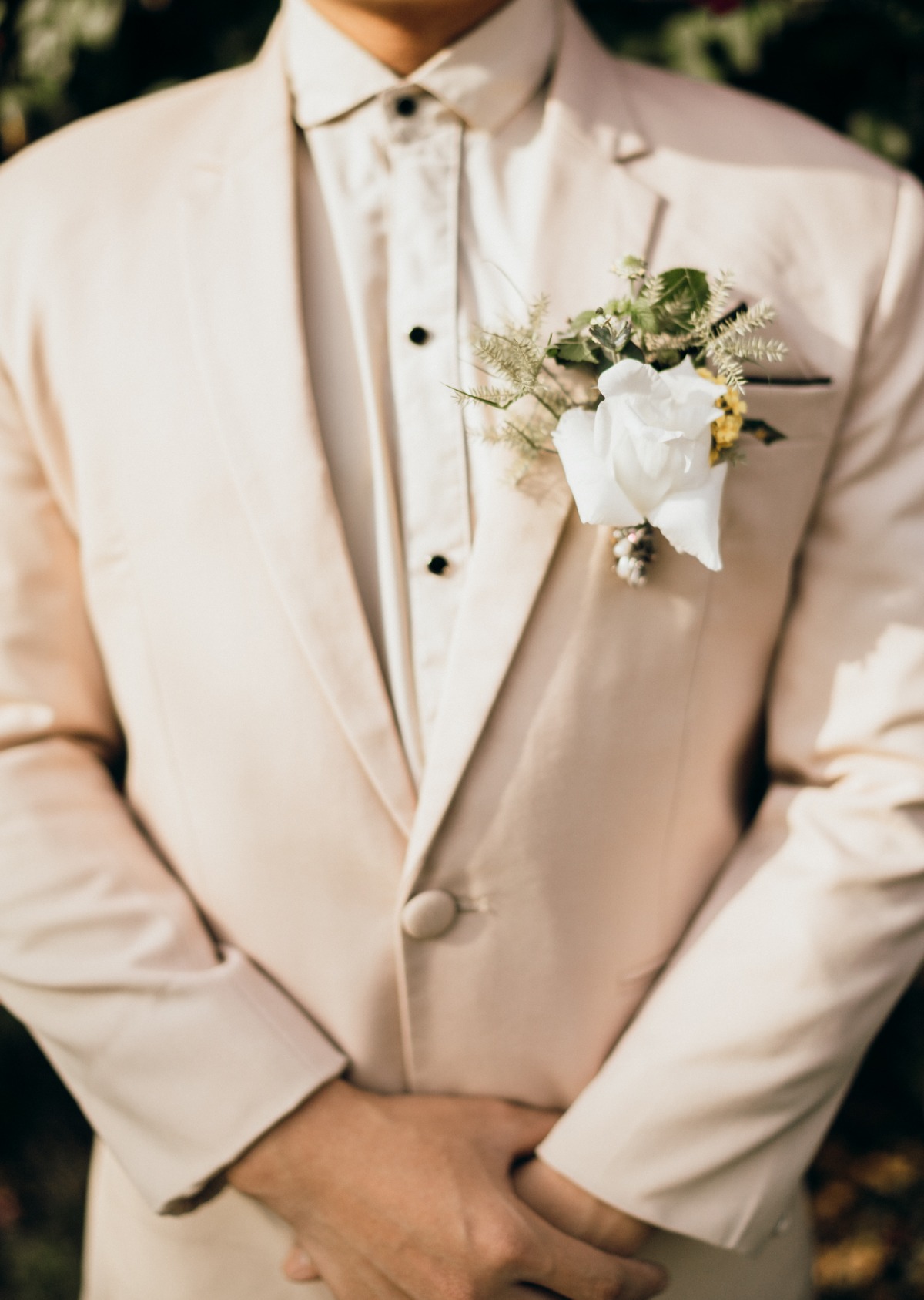 Groom in light suit with rose boutonniere close up